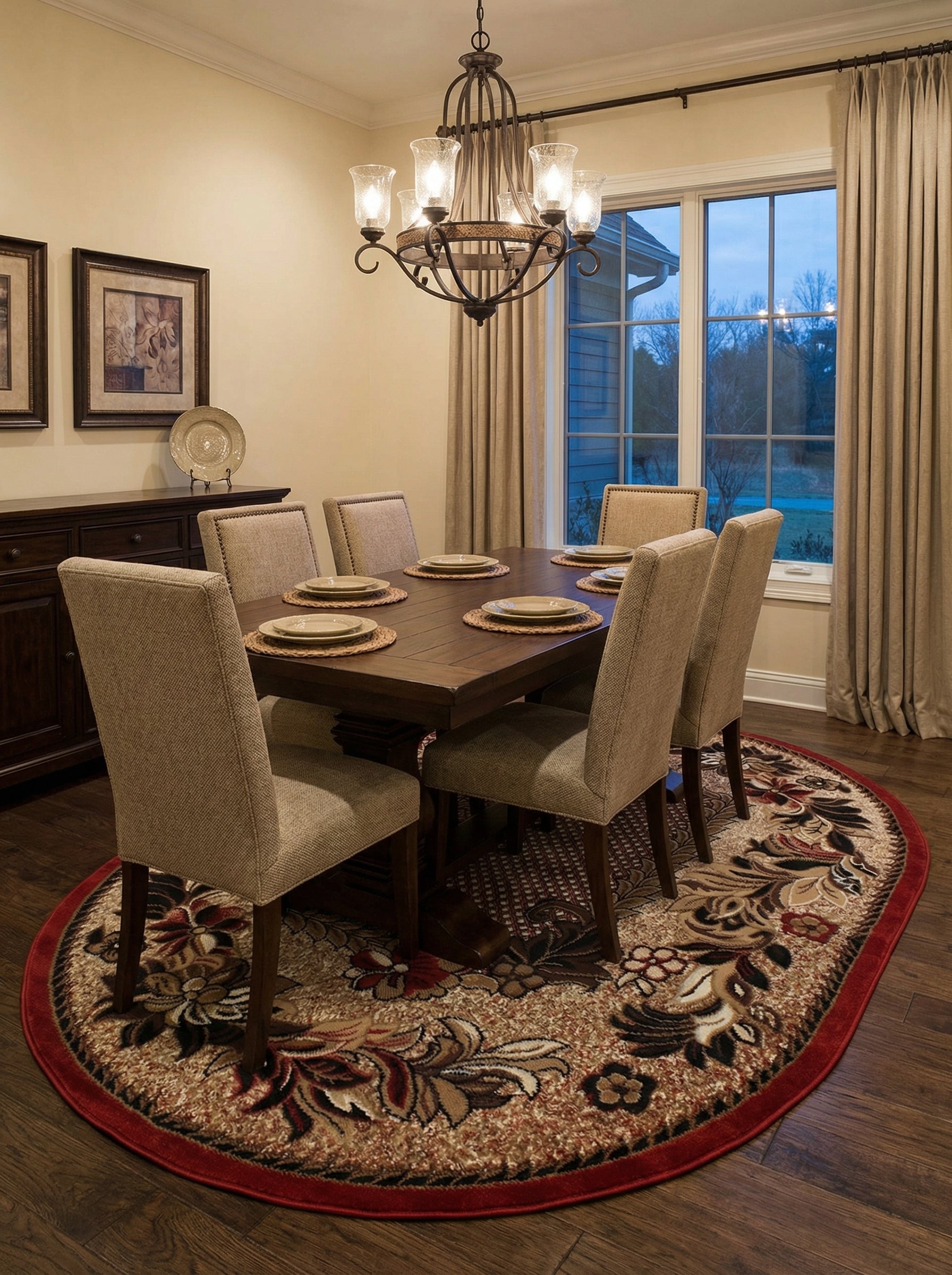 Tapis ovale beige et marron aux motifs floraux rouges et noirs élaborés, avec une bordure rouge, sous une table de salle à manger