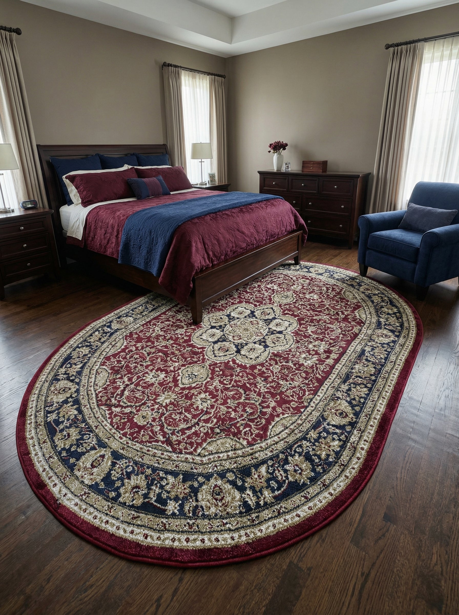Tapis ovale rouge bordeaux à motifs ornementaux crème et bleu marine, incluant un médaillon central, dans une chambre