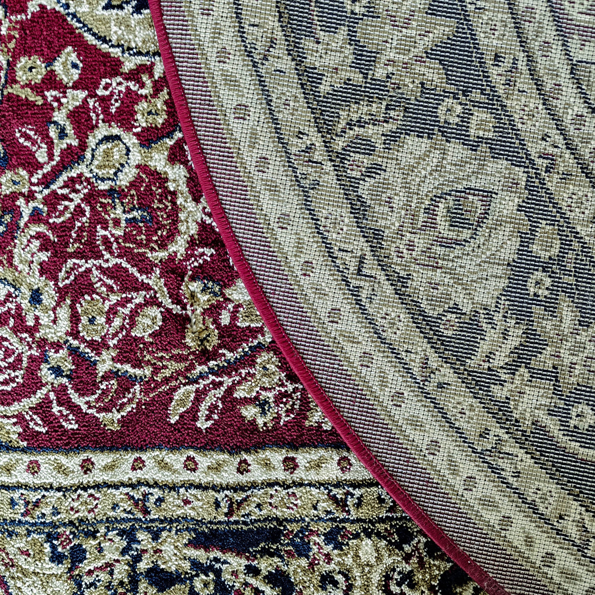 Tapis aux motifs floraux bordeaux, crème et bleus, bordé d'un liséré rouge et d'une section tissée beige à motifs géométriques foncés