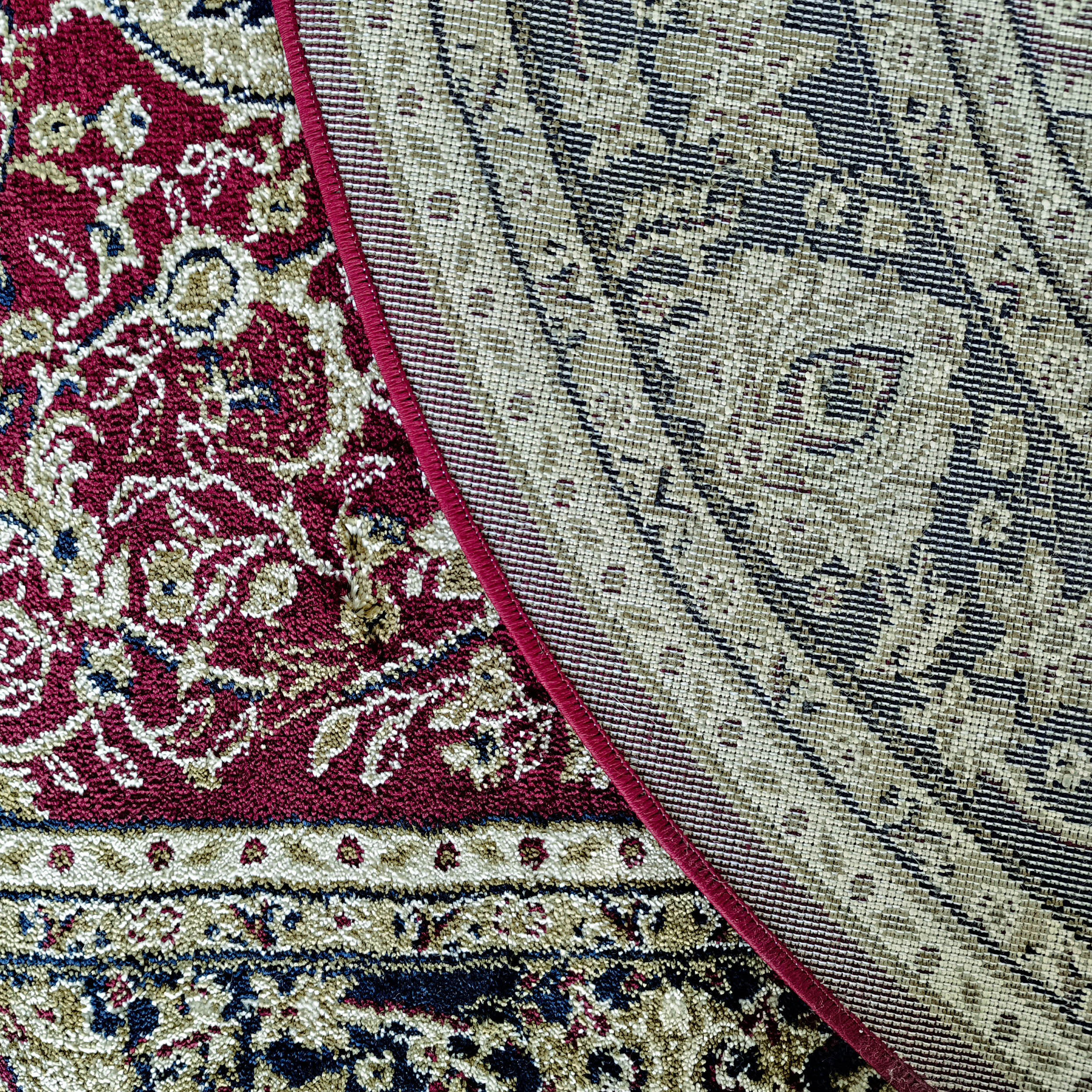 Tapis aux motifs floraux bordeaux, crème et bleus, bordé d'un liséré rouge et d'une section tissée beige à motifs géométriques foncés