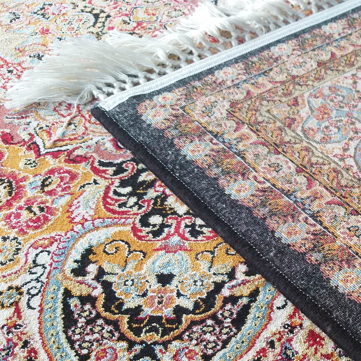Tapis multicolore à motifs orientaux complexes, avec une étiquette noire et des franges blanches