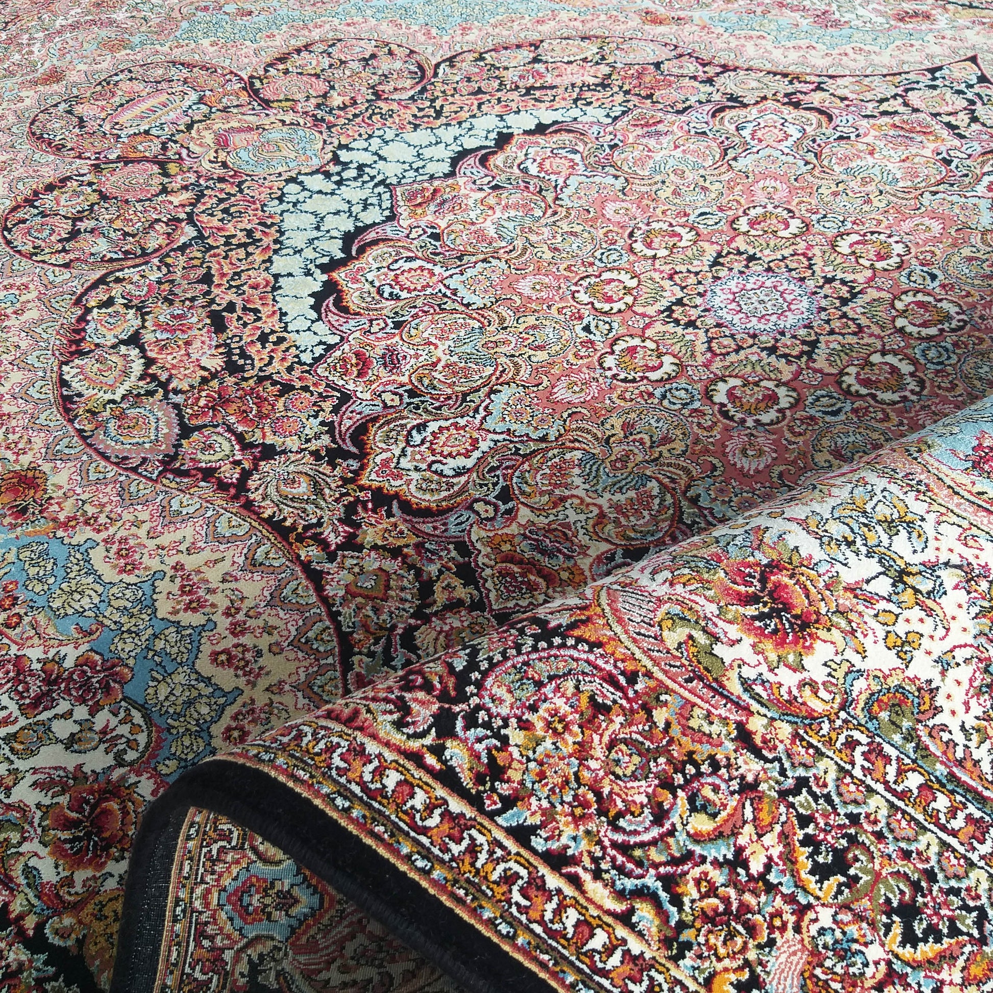 Tapis aux motifs orientaux floraux et cachemire complexes, richement coloré en rouge, rose, bleu, crème et noir, partiellement roulé