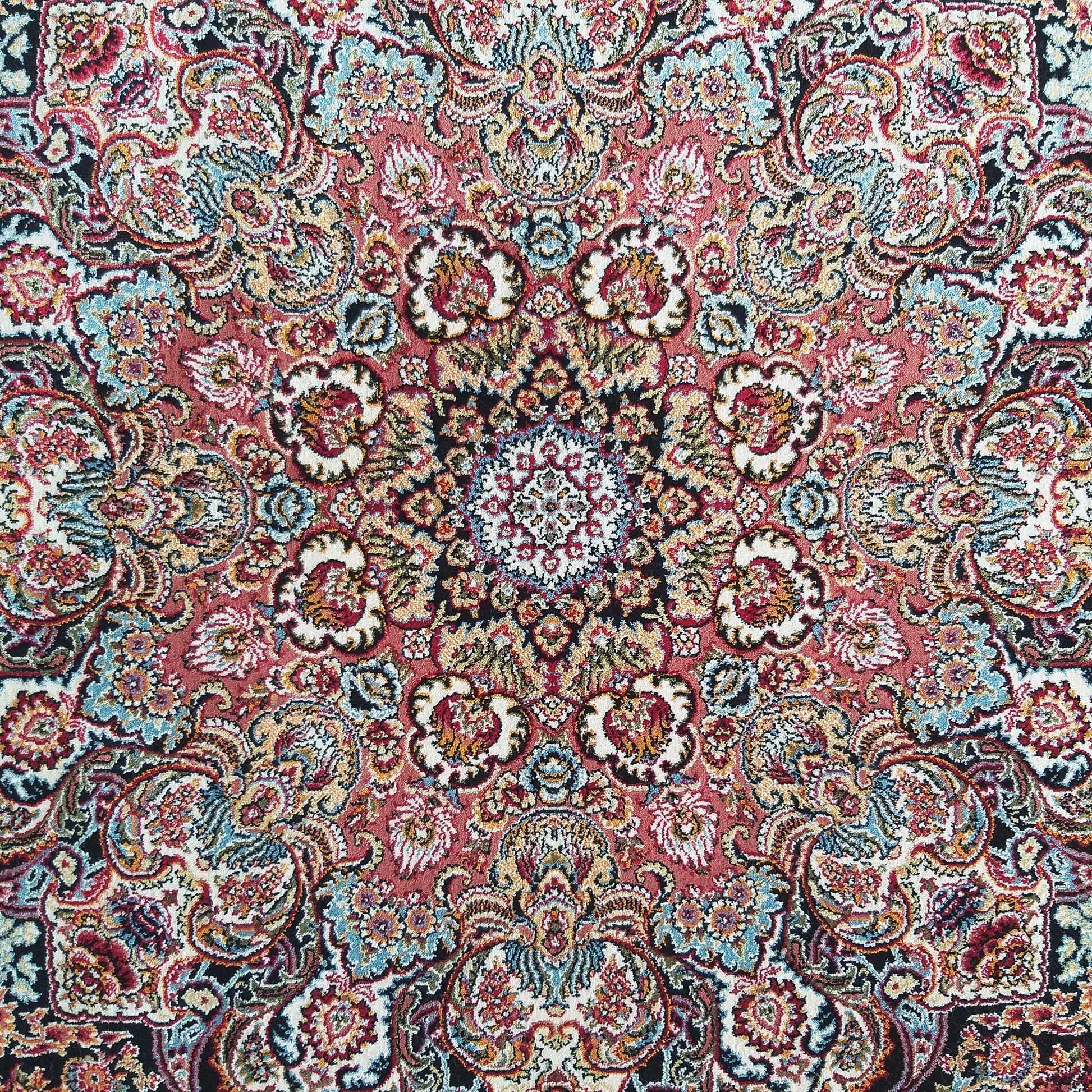 Gros plan sur un tapis orné de motifs floraux et cachemire symétriques, aux couleurs rose, bleu, or, blanc et noir