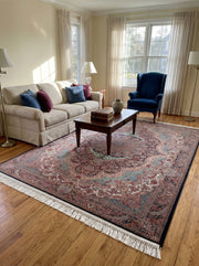 Tapis richement orné de motifs orientaux cachemire et floraux en bordeaux, bleu-vert, crème, bordure noire et franges, dans un salon