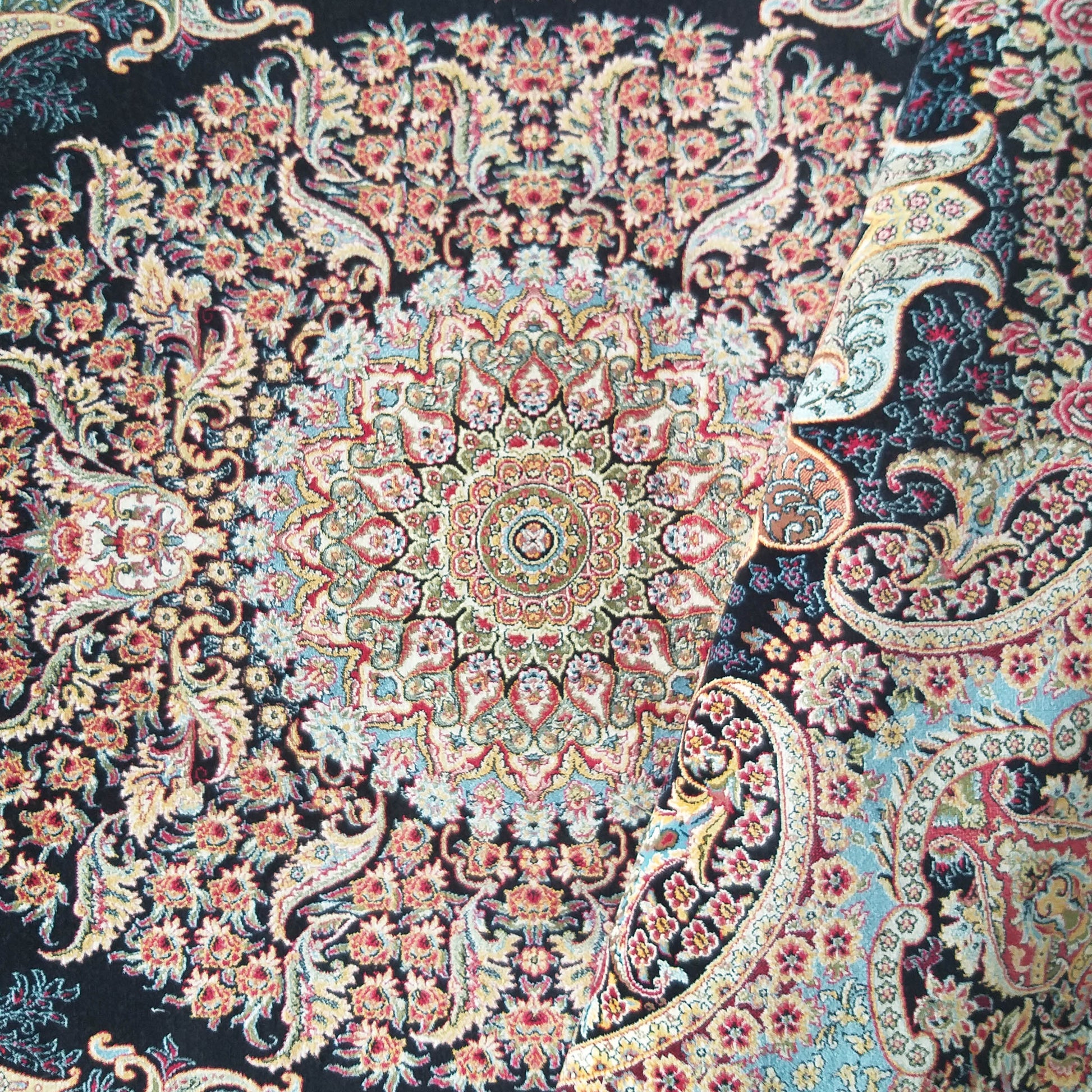 Tapis orné de motifs floraux et cachemire complexes, aux couleurs vives rouge, or et bleu sur un fond noir