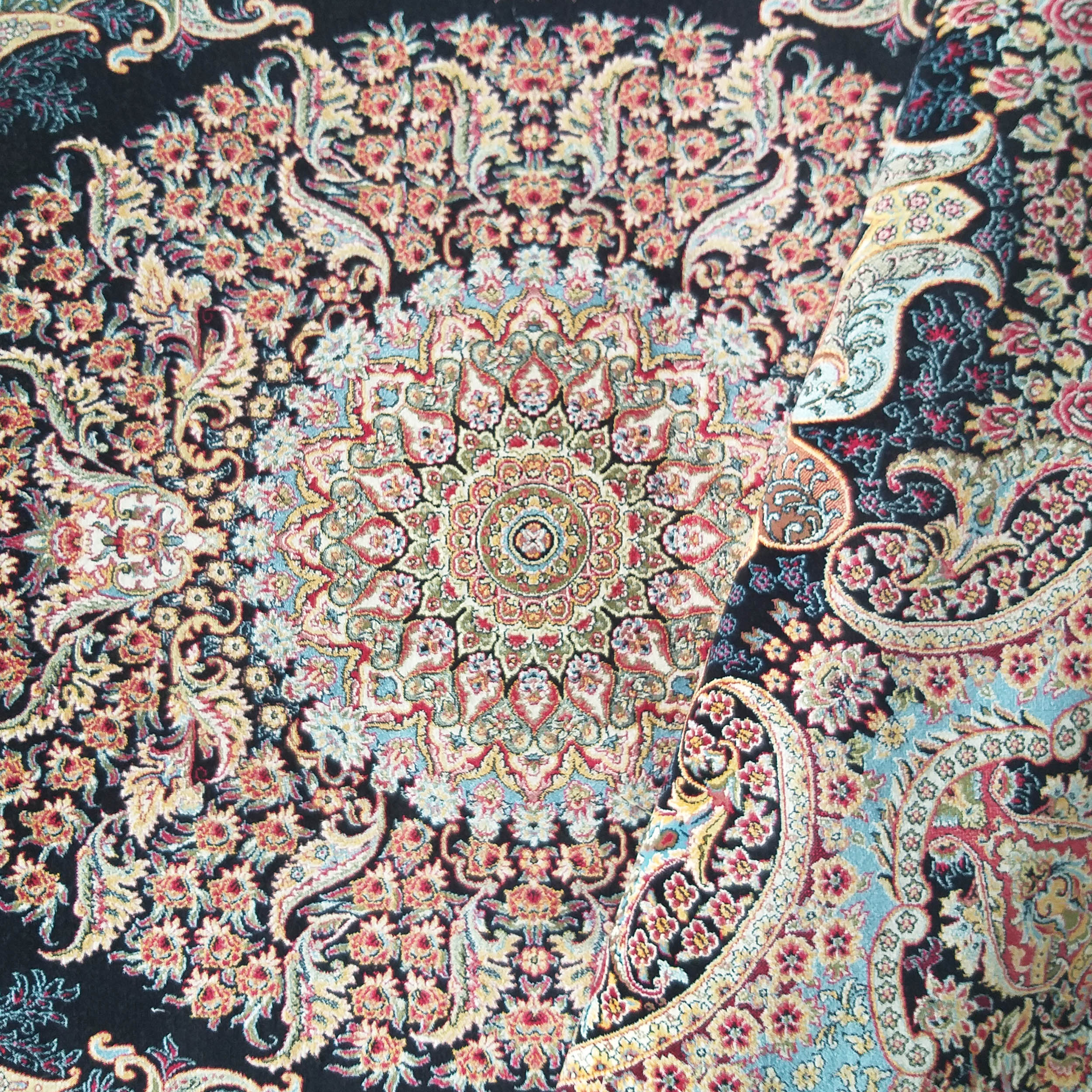 Tapis orné de motifs floraux et cachemire complexes, aux couleurs vives rouge, or et bleu sur un fond noir