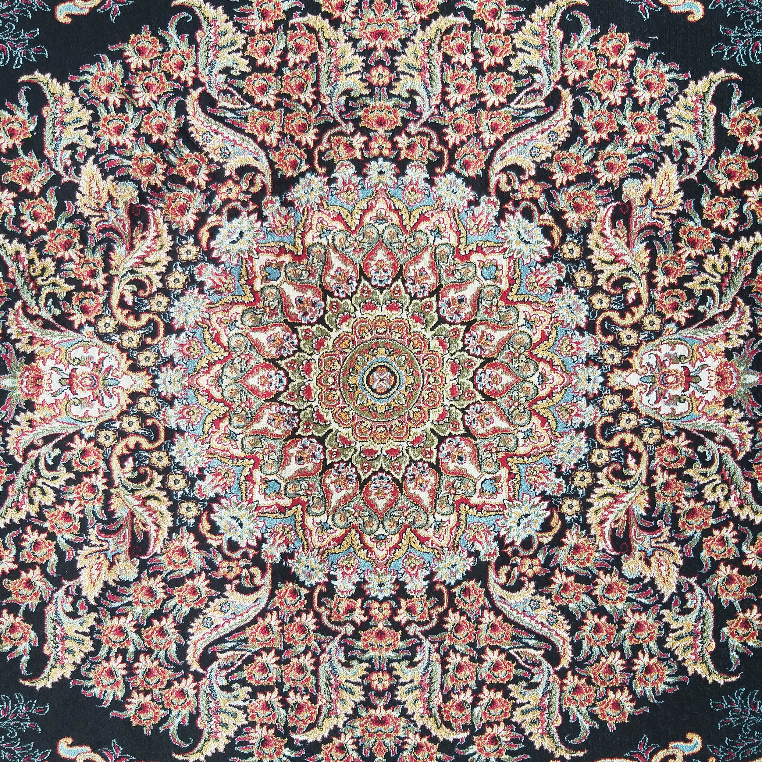 Tapis floral très détaillé et symétrique, centré sur un médaillon, aux couleurs vives rouge, or, vert et bleu ciel sur fond noir