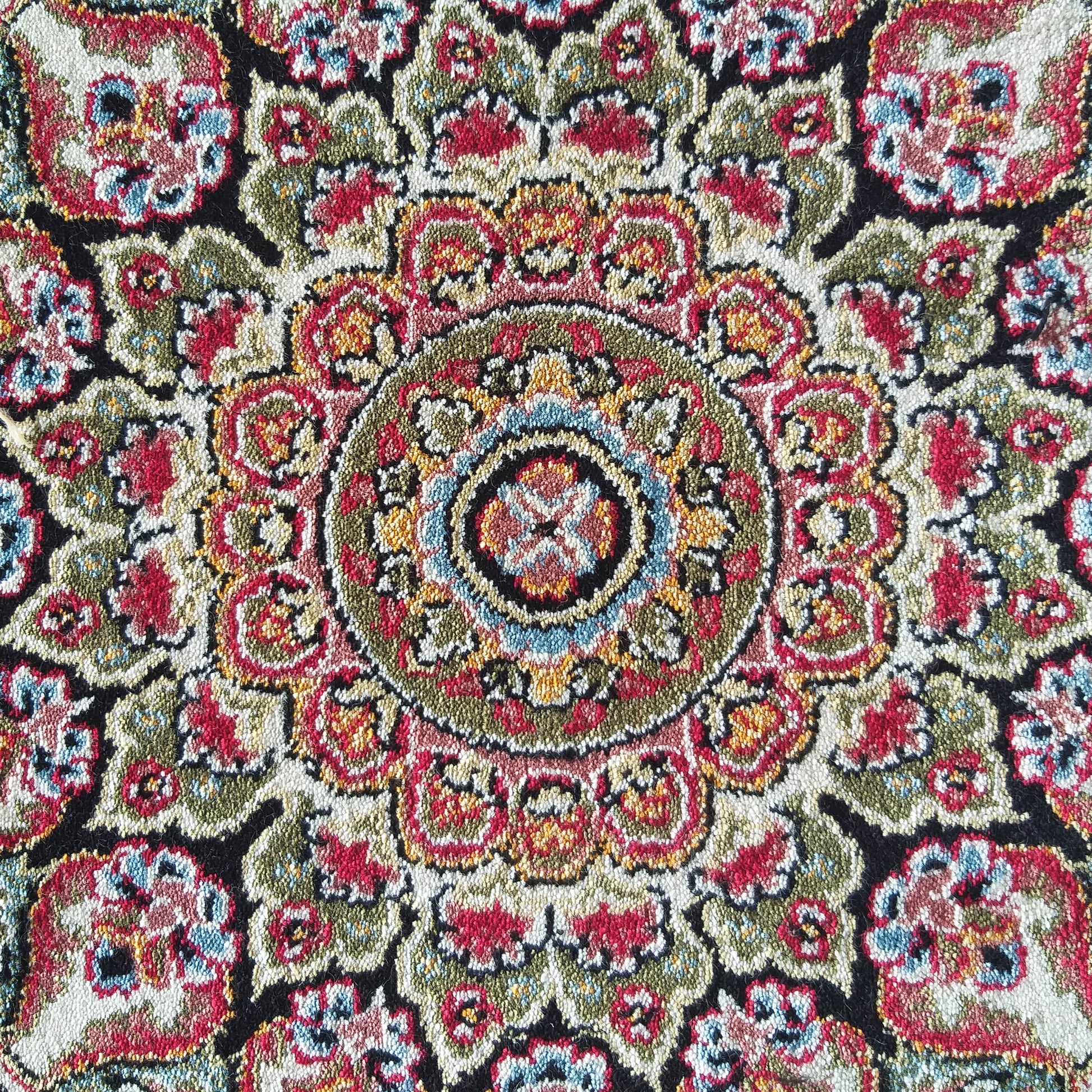 Tapis textile aux motifs complexes, coloré de rouge, vert, crème, noir, bleu et jaune