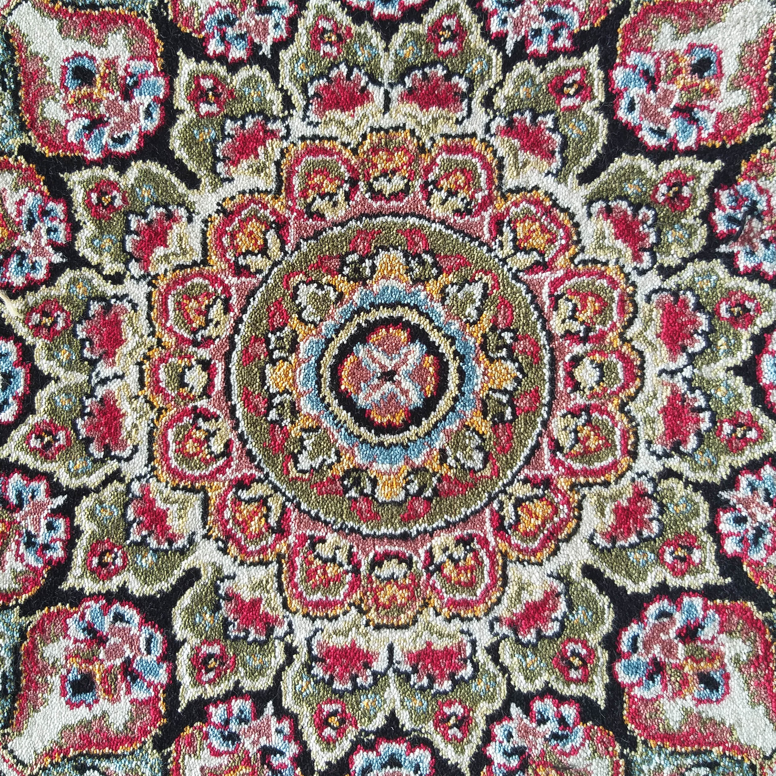 Tapis textile aux motifs complexes, coloré de rouge, vert, crème, noir, bleu et jaune