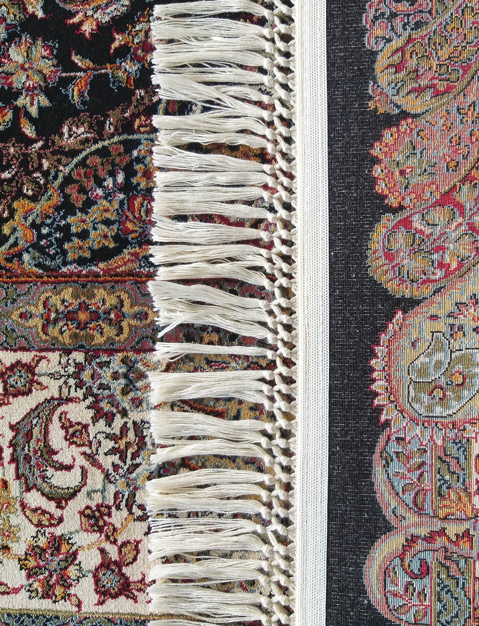 Tapis richement orné de motifs floraux et cachemire multicolores sur fonds sombres et clairs, avec des franges claires