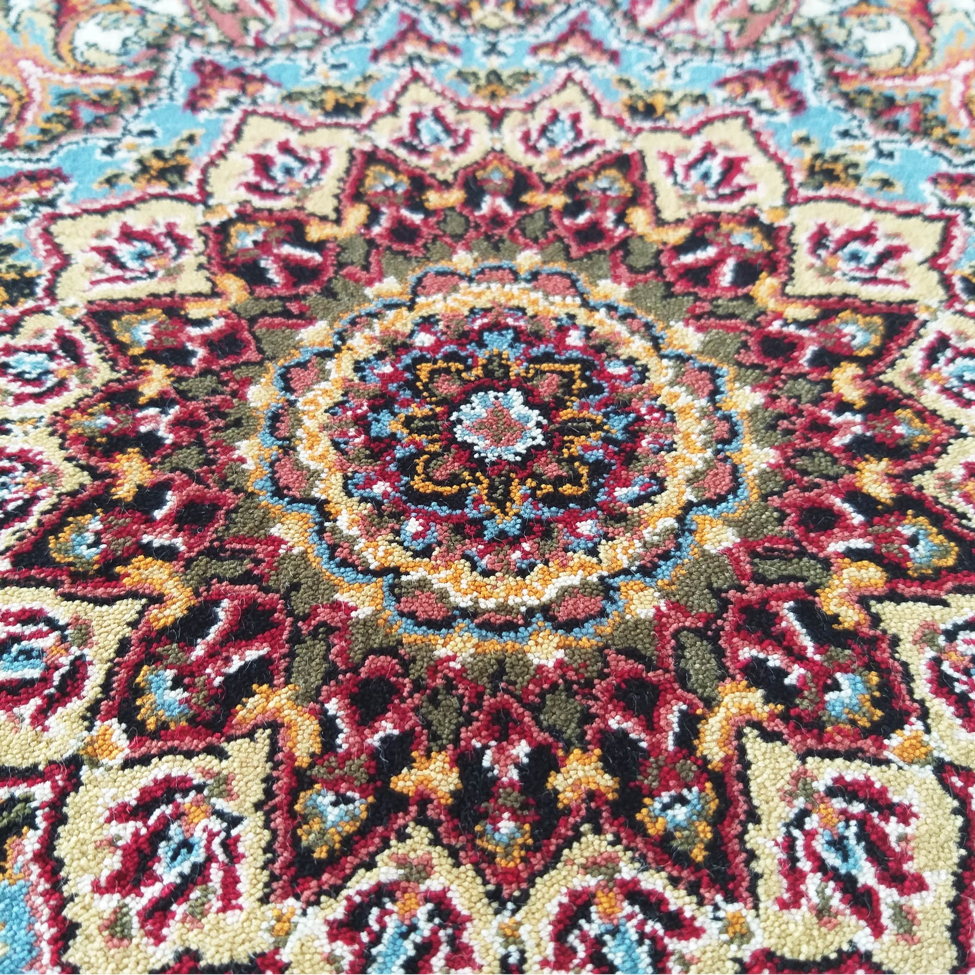 Tapis multicolore en gros plan avec un médaillon central et des motifs floraux traditionnels rouge, bleu, jaune, vert olive et noir