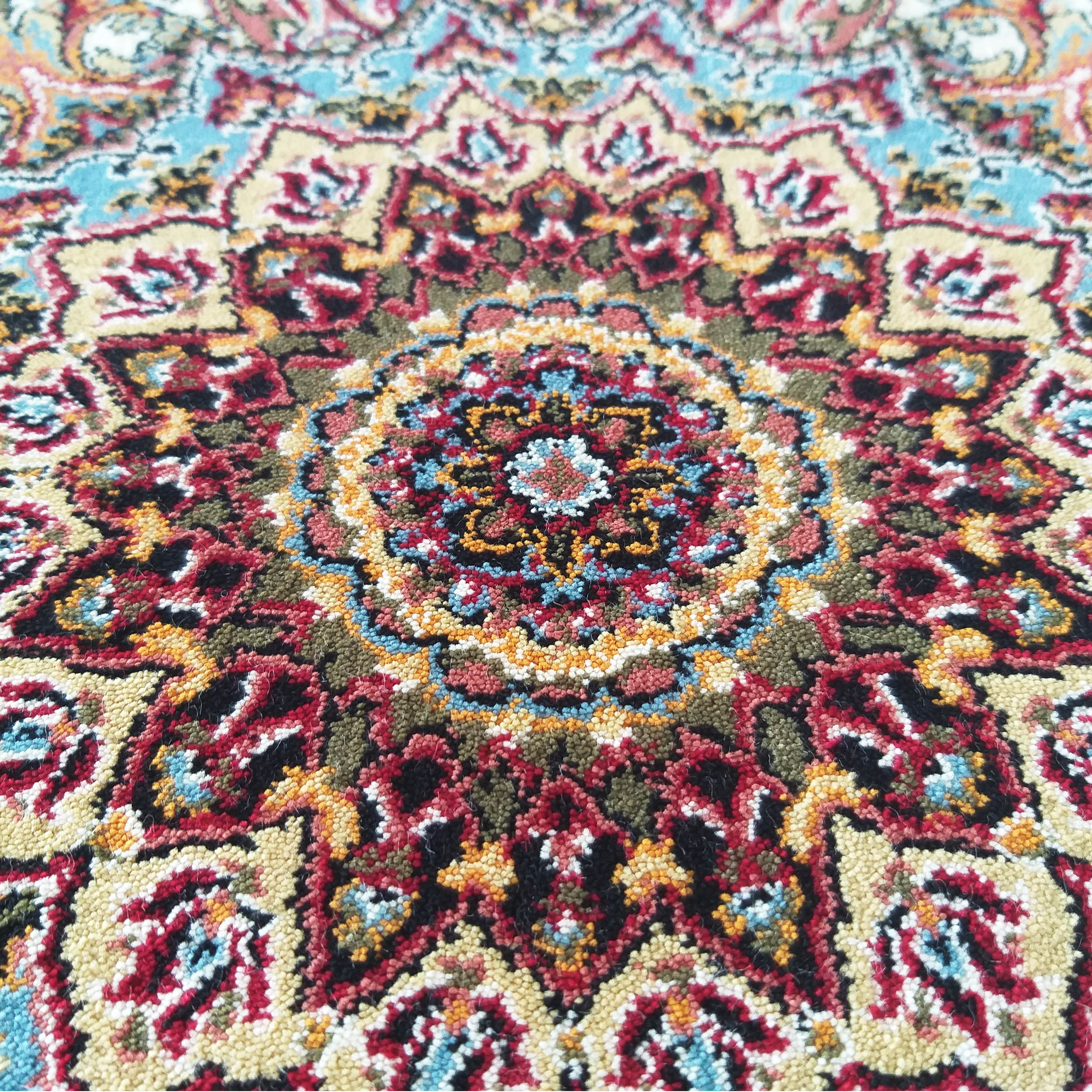 Tapis multicolore en gros plan avec un médaillon central et des motifs floraux traditionnels rouge, bleu, jaune, vert olive et noir