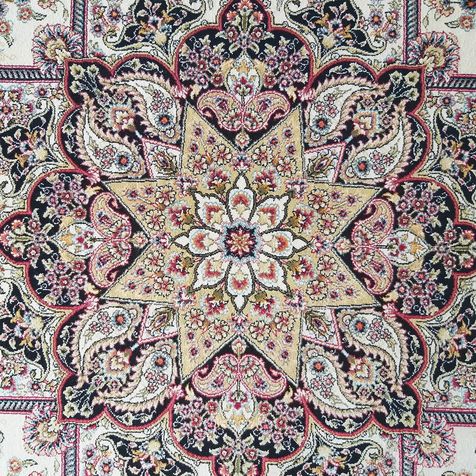 Tapis aux motifs floraux et cachemires complexes, avec un médaillon étoilé doré sur fond noir, détails rouges et crème