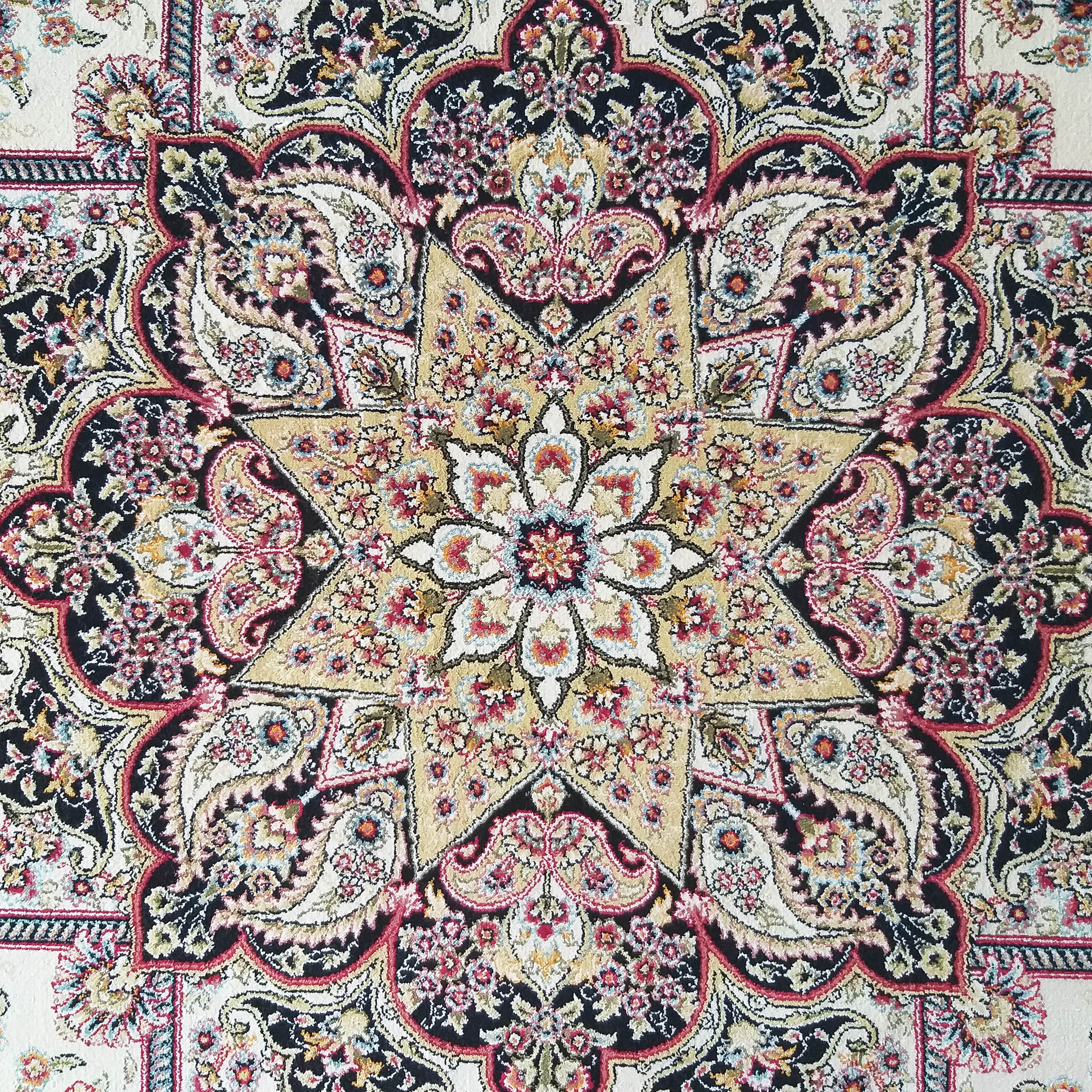 Tapis aux motifs floraux et cachemires complexes, avec un médaillon étoilé doré sur fond noir, détails rouges et crème