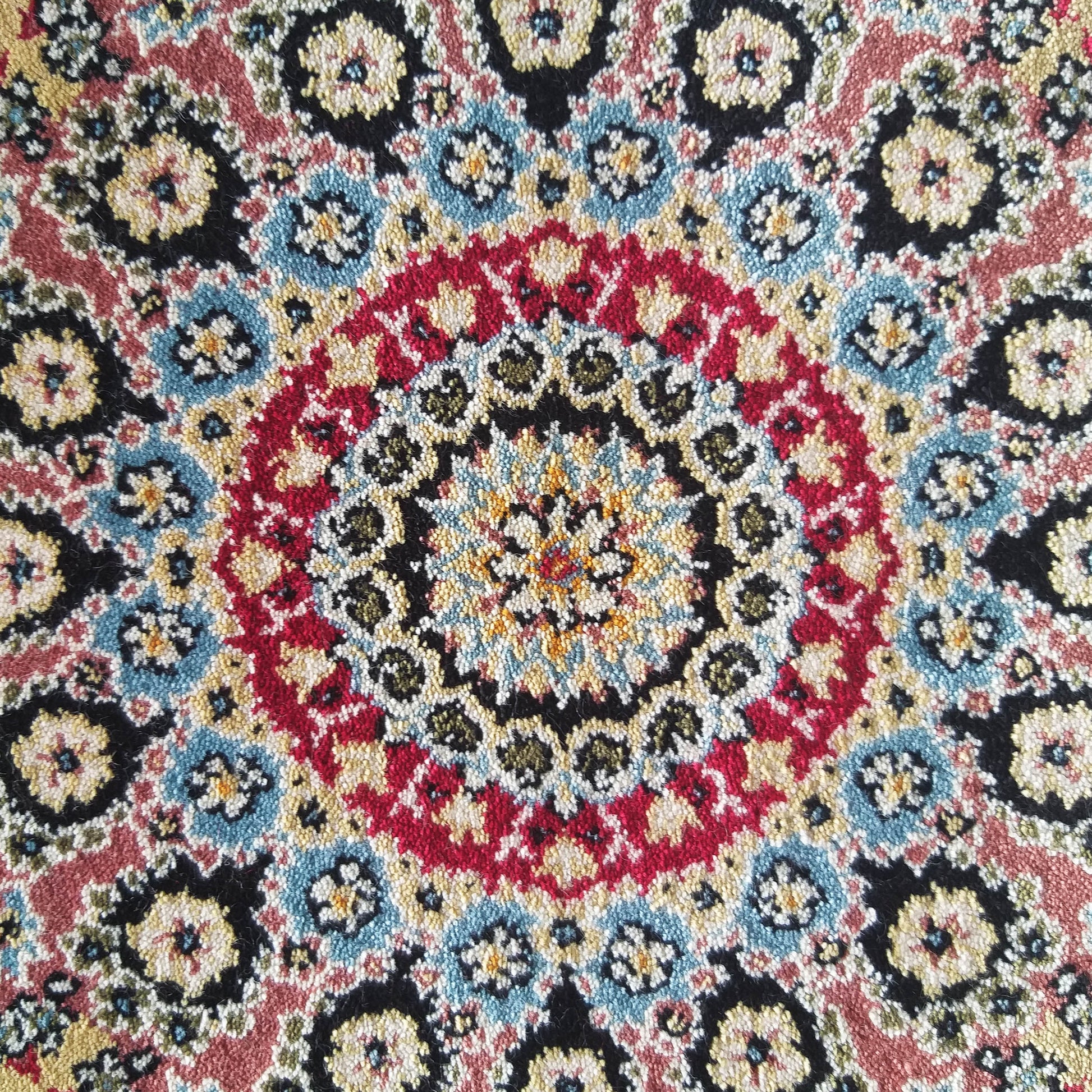 Tapis à motifs orientaux colorés, avec un dessin floral central circulaire rouge, bleu, jaune et noir