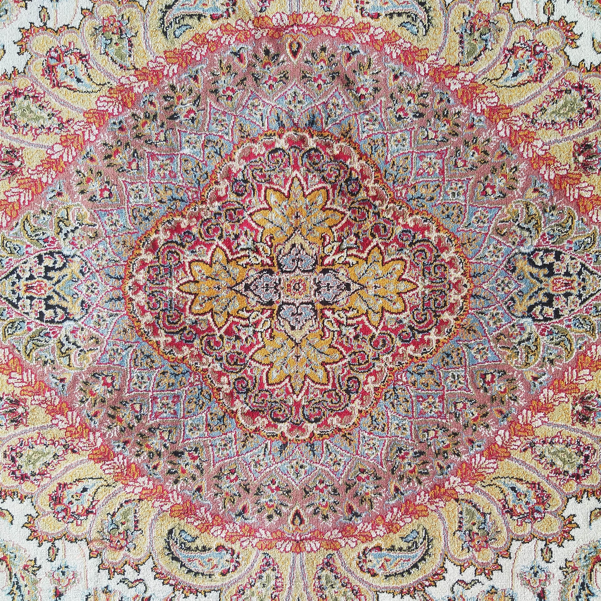Tapis aux riches motifs orientaux et médaillon central, teintes de rouge, jaune, bleu pâle et blanc cassé