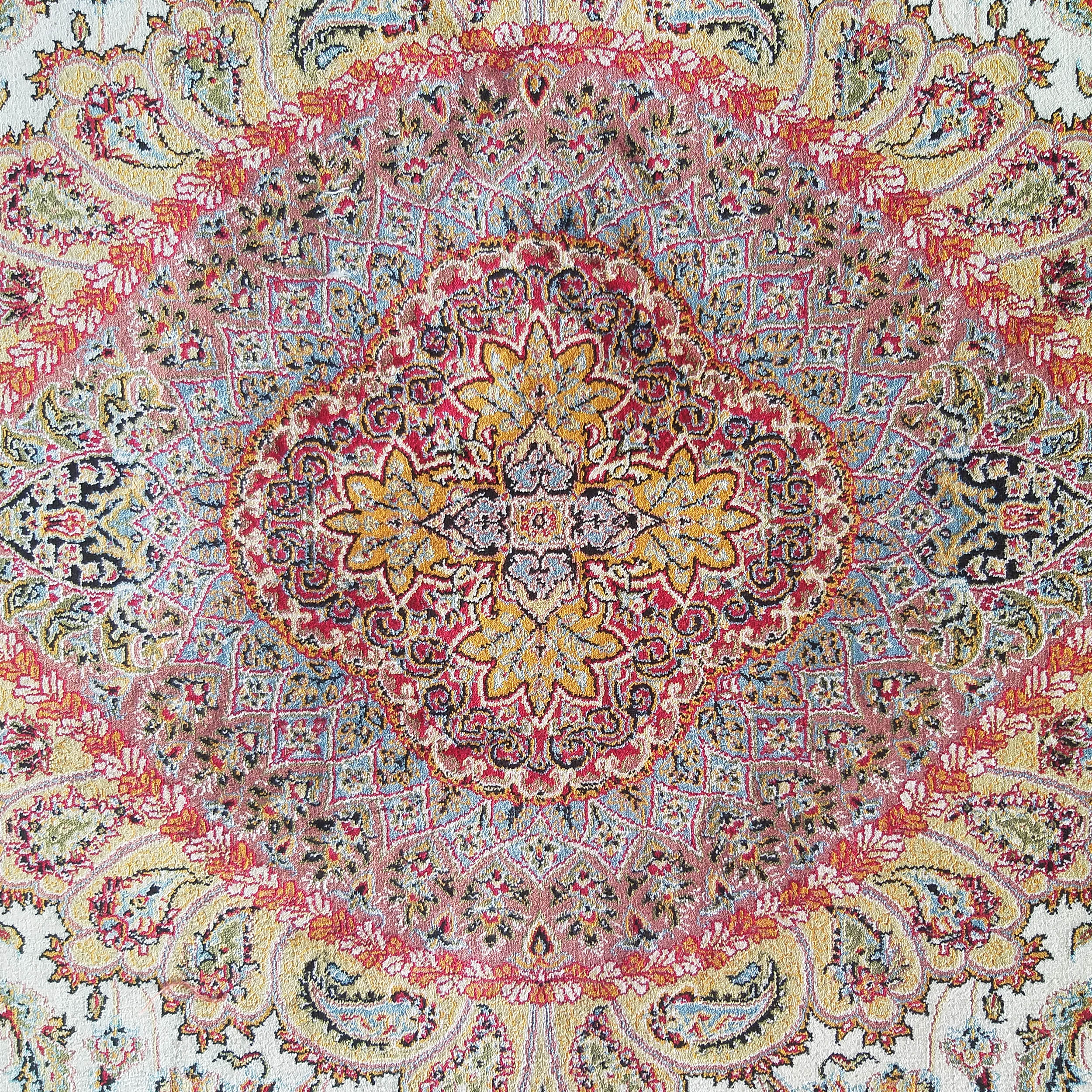 Tapis aux riches motifs orientaux et médaillon central, teintes de rouge, jaune, bleu pâle et blanc cassé