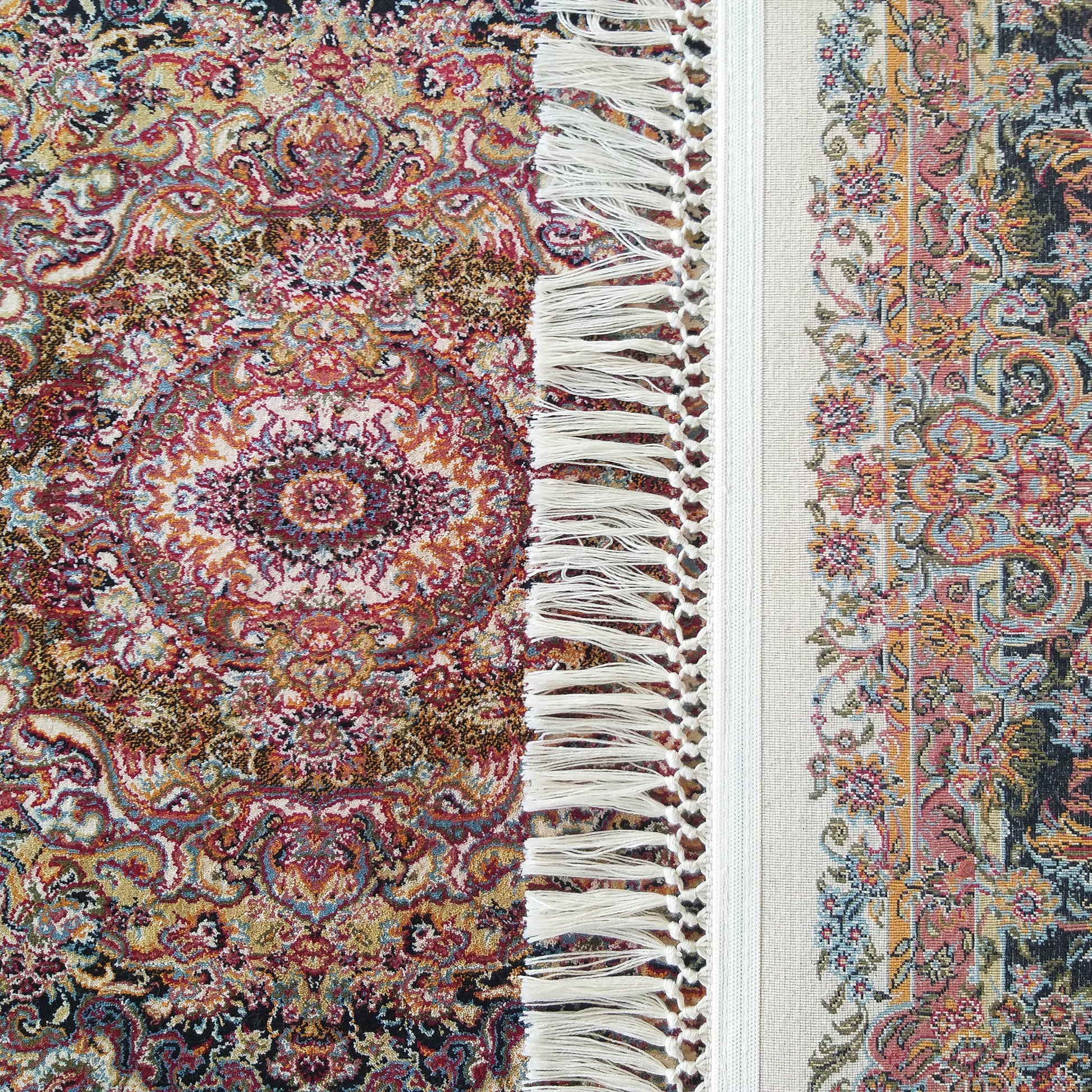 Tapis orné de motifs floraux multicolores avec un médaillon central, bordé de franges blanches et d'une bande claire décorée