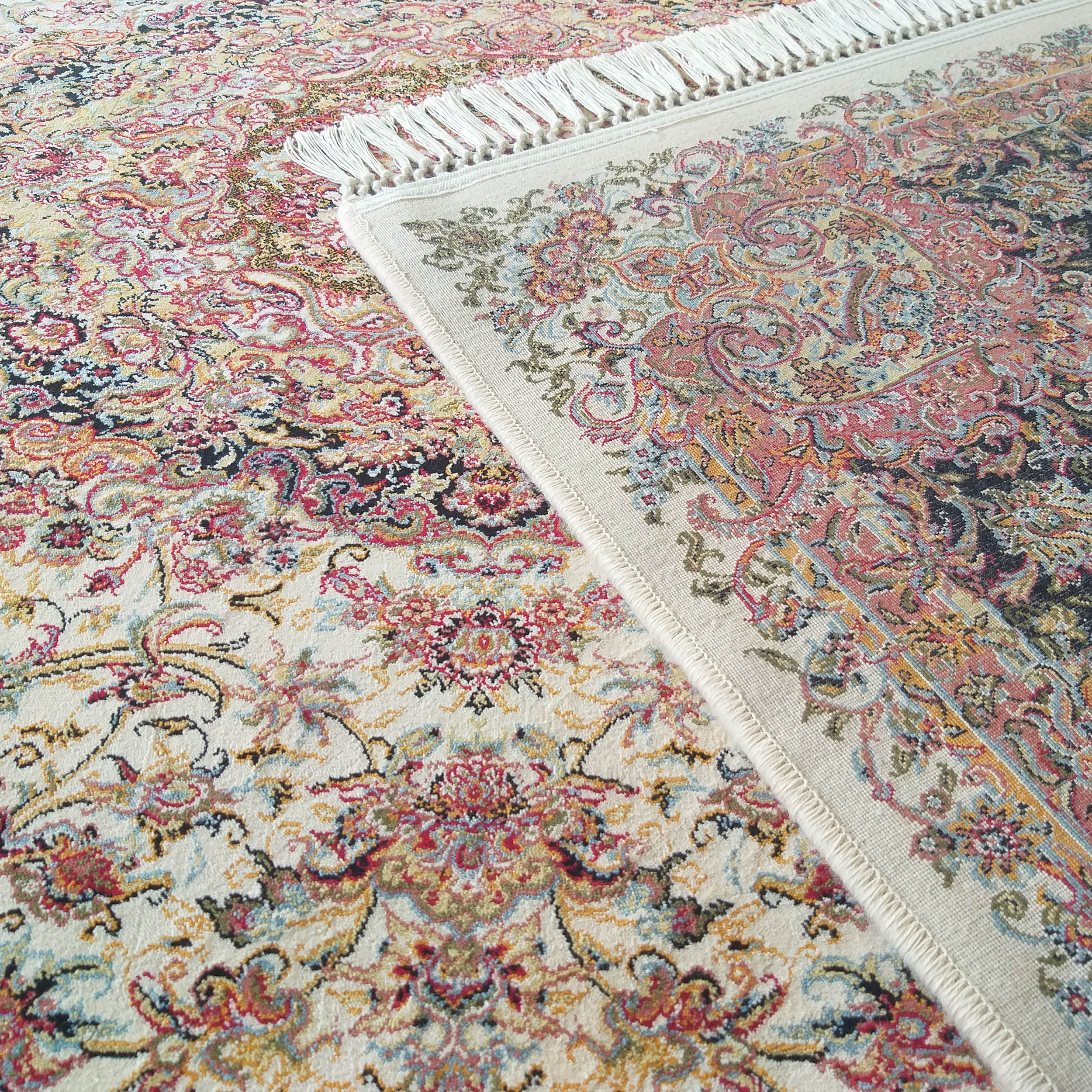 Tapis à motifs floraux et cachemire multicolores (rouge, bleu, or, noir) sur fond crème, avec des franges blanches apparentes