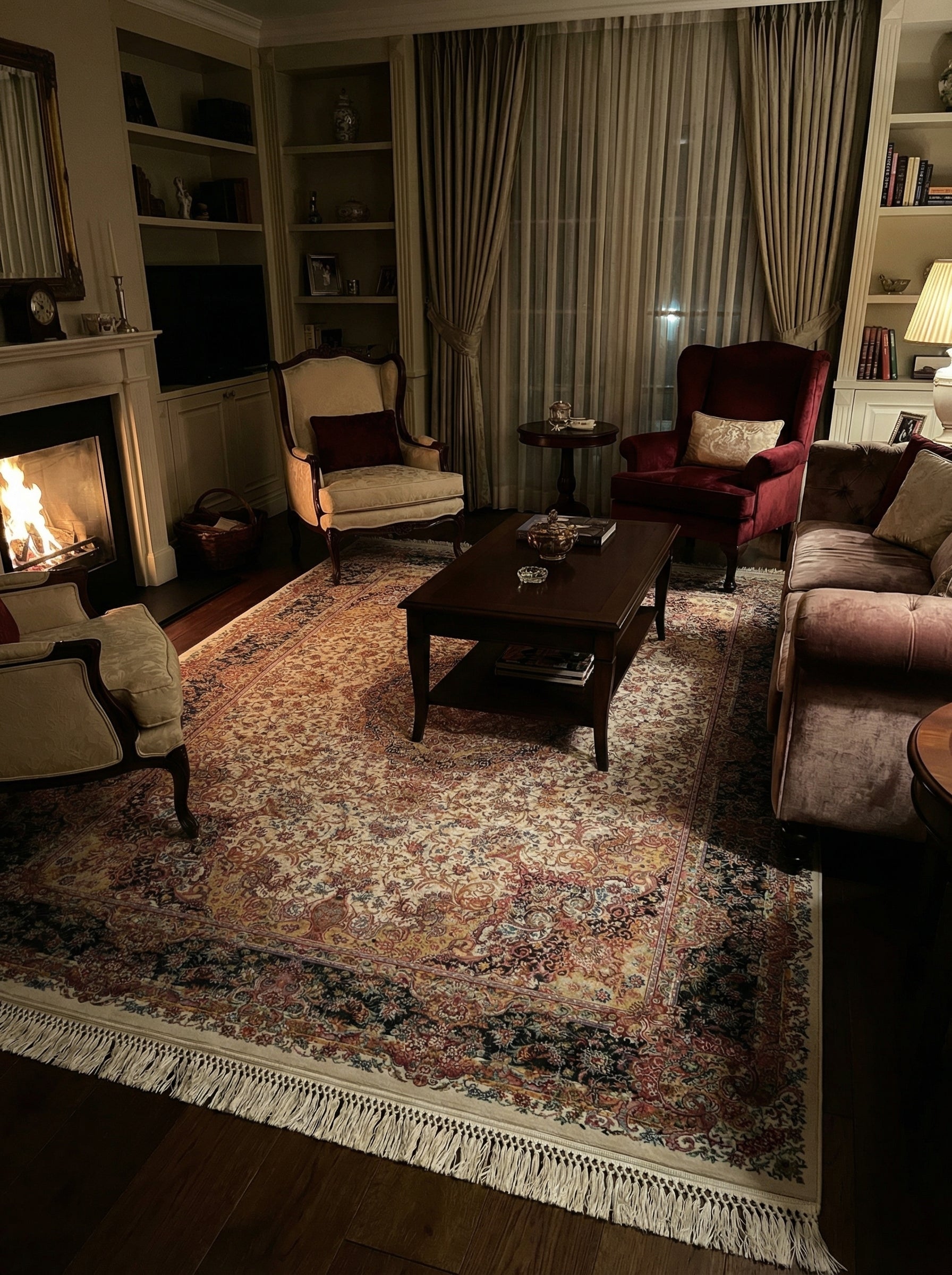 Tapis rectangulaire à motifs floraux complexes crème, rouge, doré et bleu foncé avec franges, dans un salon chaleureux