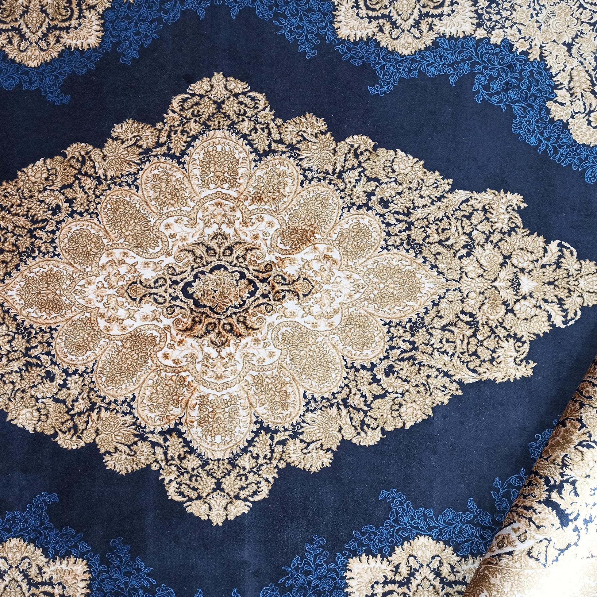 Tapis bleu nuit avec un grand motif médaillon central doré et beige et des arabesques florales bleues claires