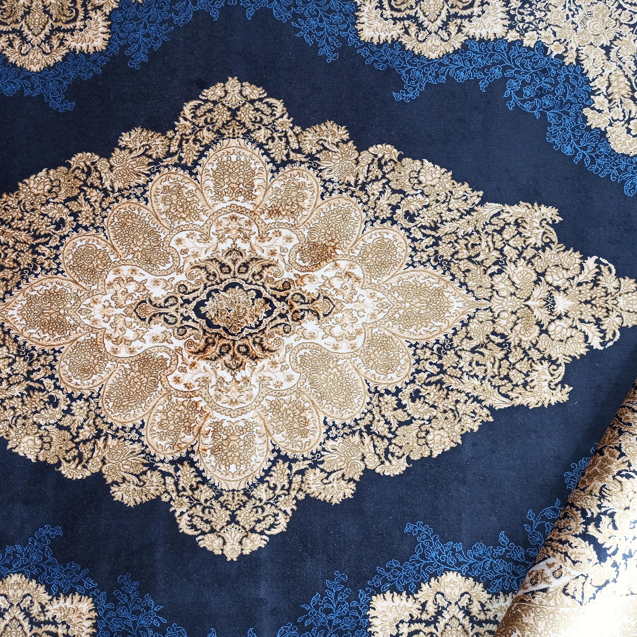 Tapis bleu nuit avec un grand motif médaillon central doré et beige et des arabesques florales bleues claires