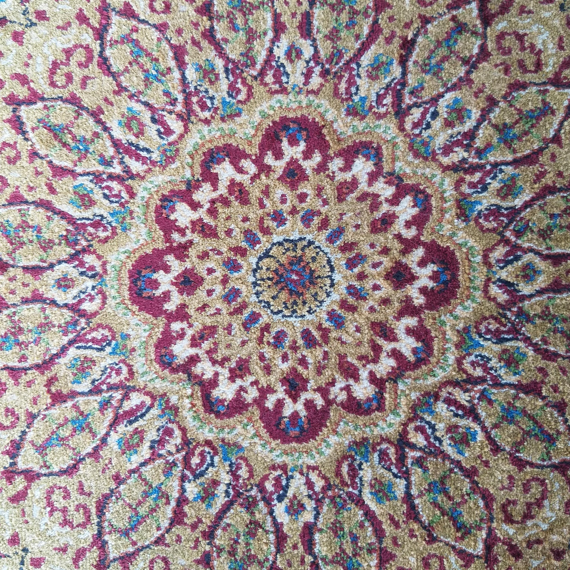 Tapis à la texture riche et aux motifs floraux complexes, or, rouge, bleu et vert, avec un médaillon central