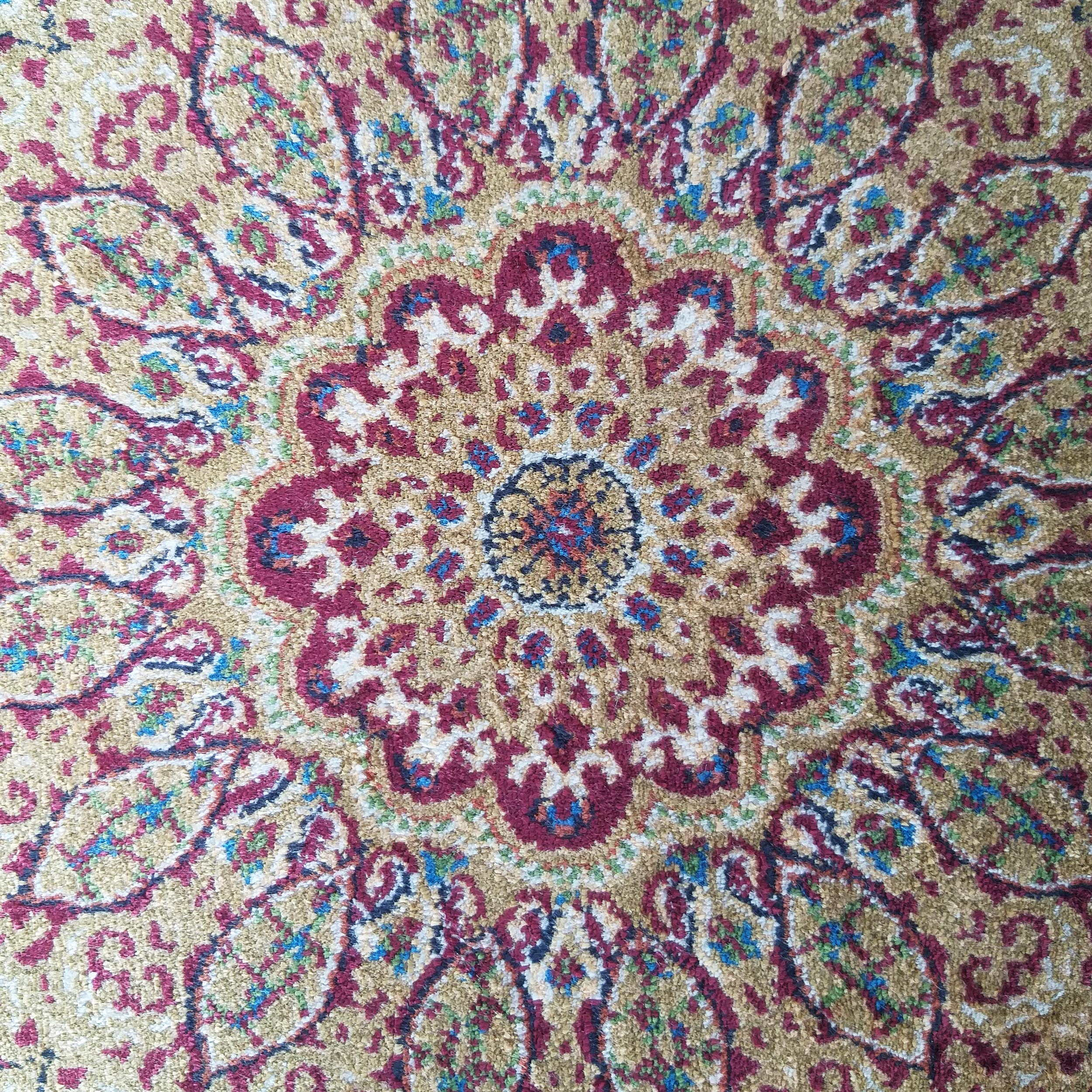 Tapis à la texture riche et aux motifs floraux complexes, or, rouge, bleu et vert, avec un médaillon central