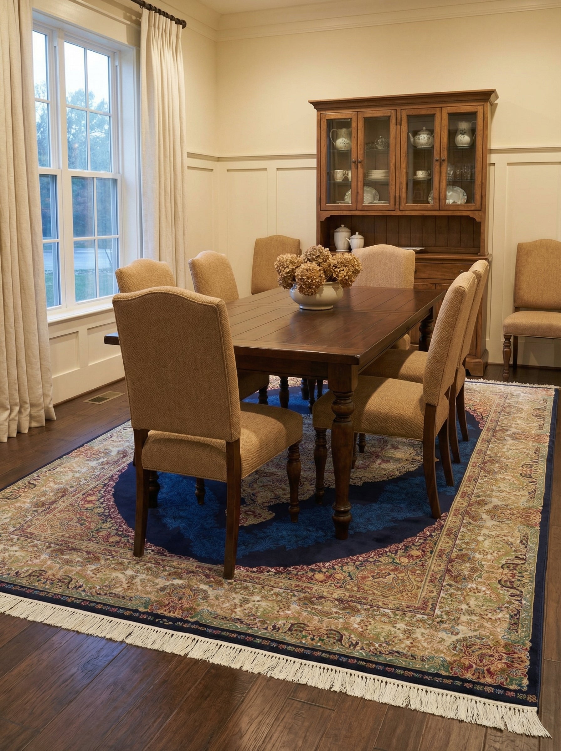 Tapis rectangulaire bleu nuit, motifs floraux traditionnels crème, rouges et or, franges, dans une salle à manger