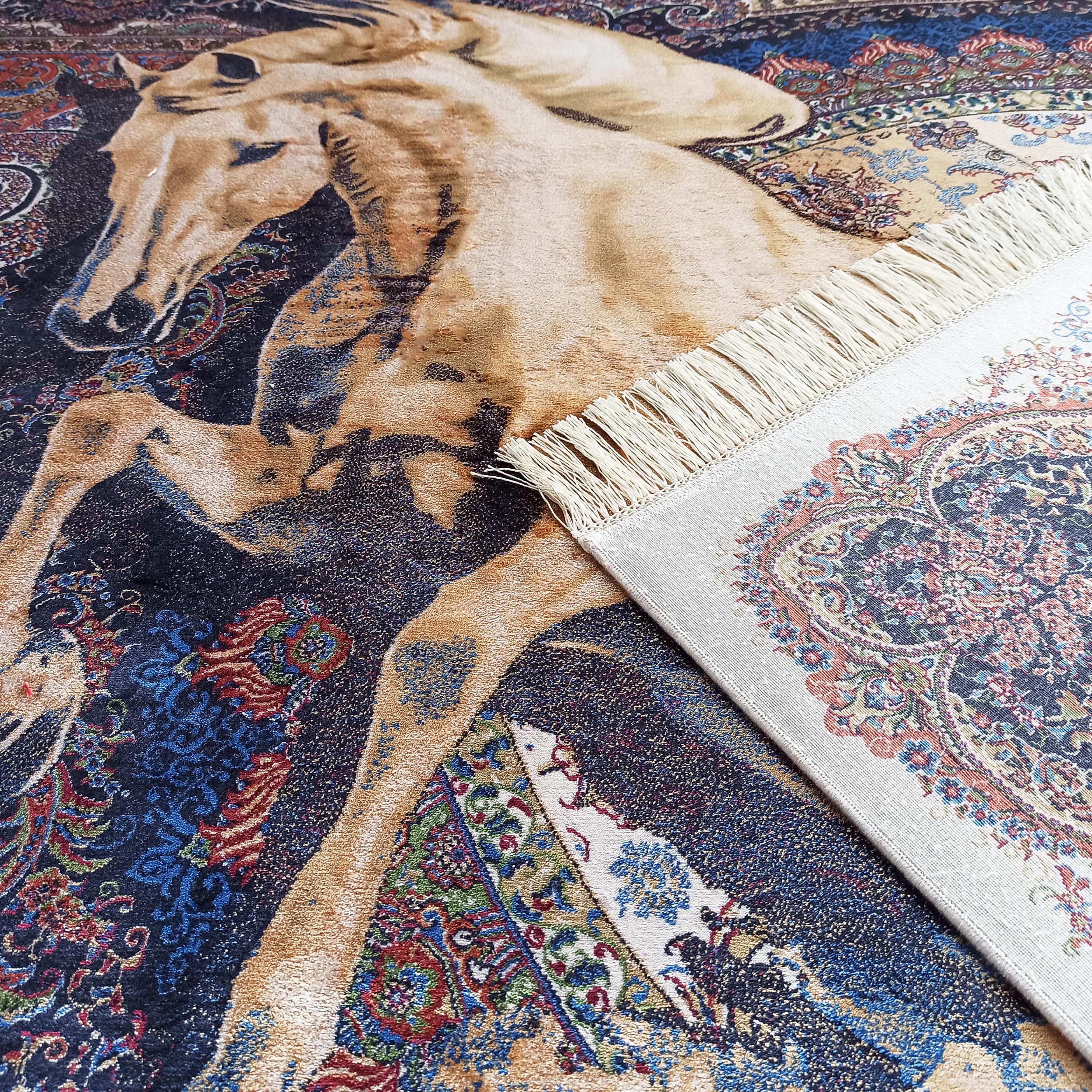 Tapis coloré avec un cheval beige sur fond bleu foncé, richement orné de motifs ornementaux et de franges claires