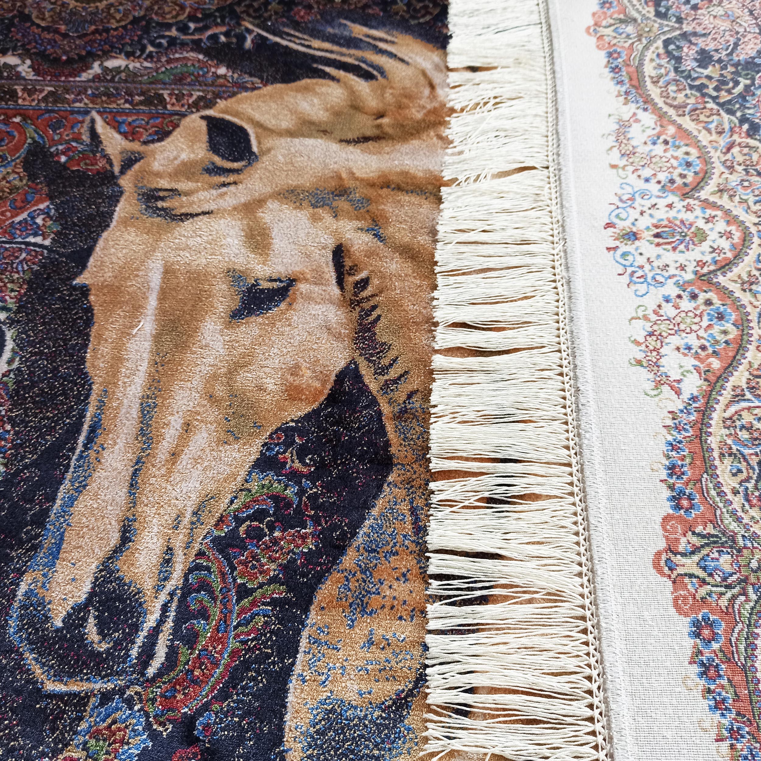 Un tapis sombre à tête de cheval marron côtoie un tapis clair aux arabesques multicolores, tous deux ornés de franges