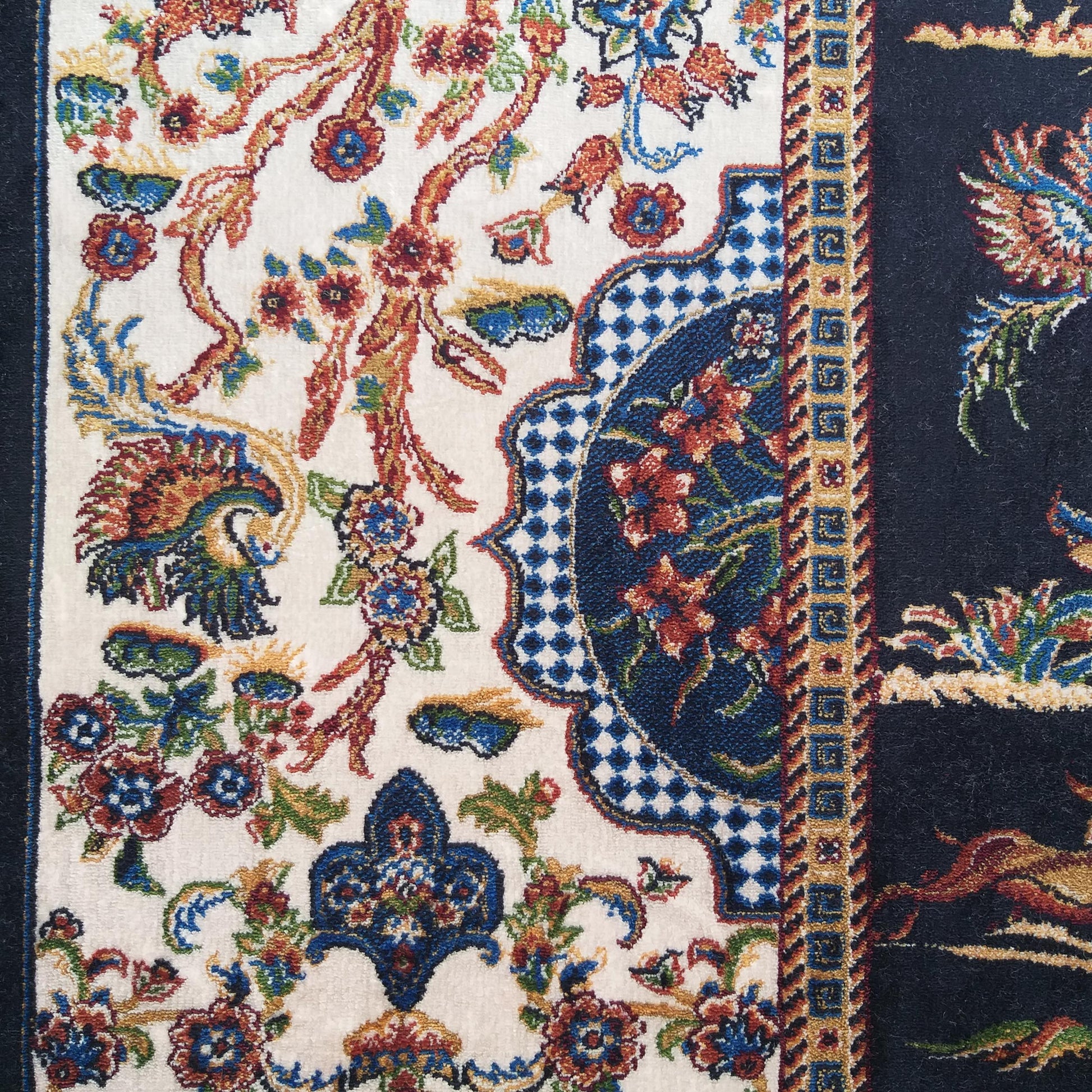 Tapis ornemental aux motifs floraux et arabesques en rouge, bleu, or et vert sur fond crème et bleu marine