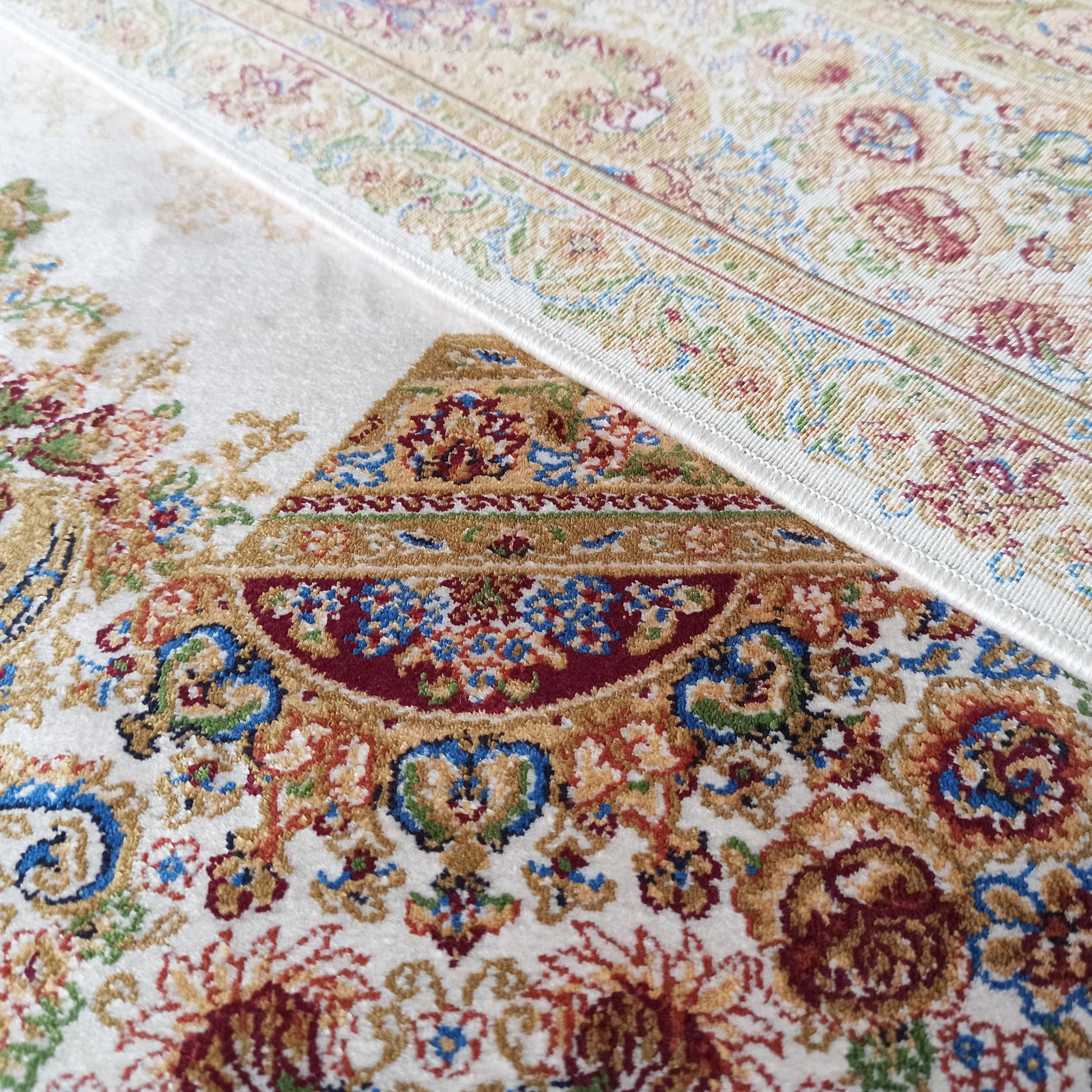 Tapis à motifs floraux et ornementaux rouges, bleus et dorés sur fond crème