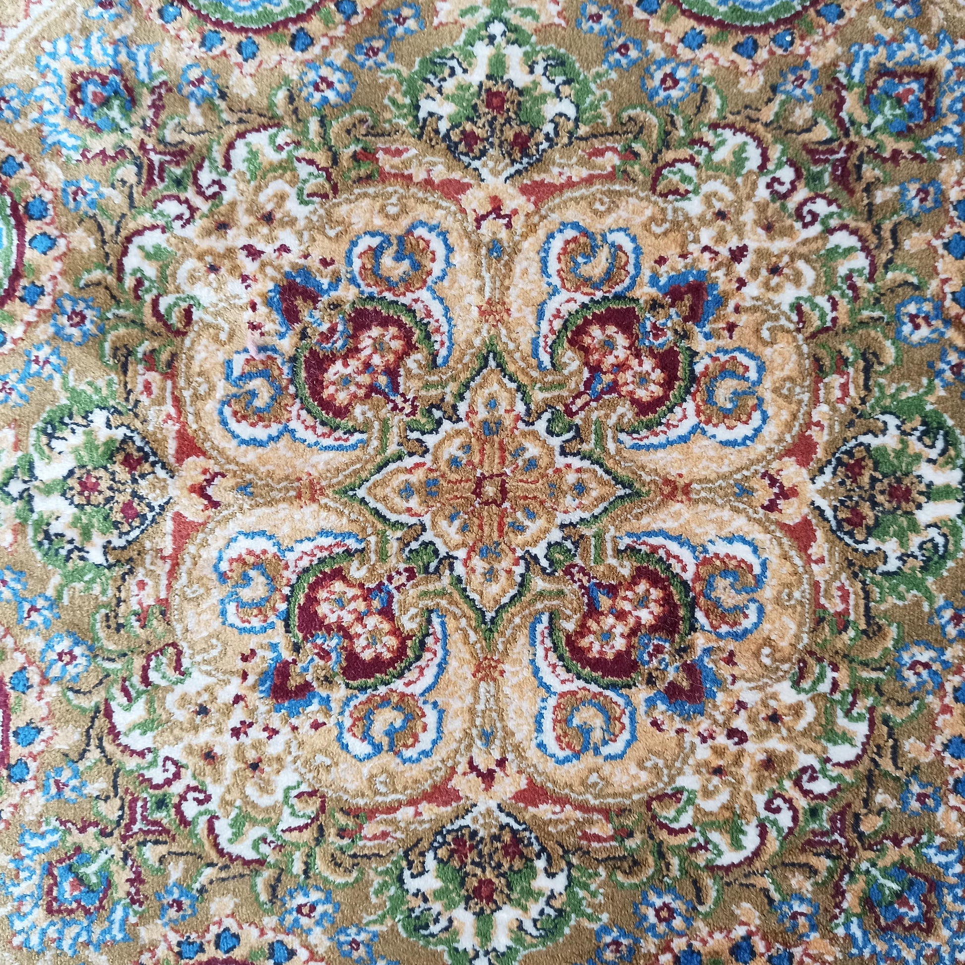 Tapis aux motifs ornementaux et floraux riches en beige, bleu, rouge, vert et blanc cassé, avec une texture douce
