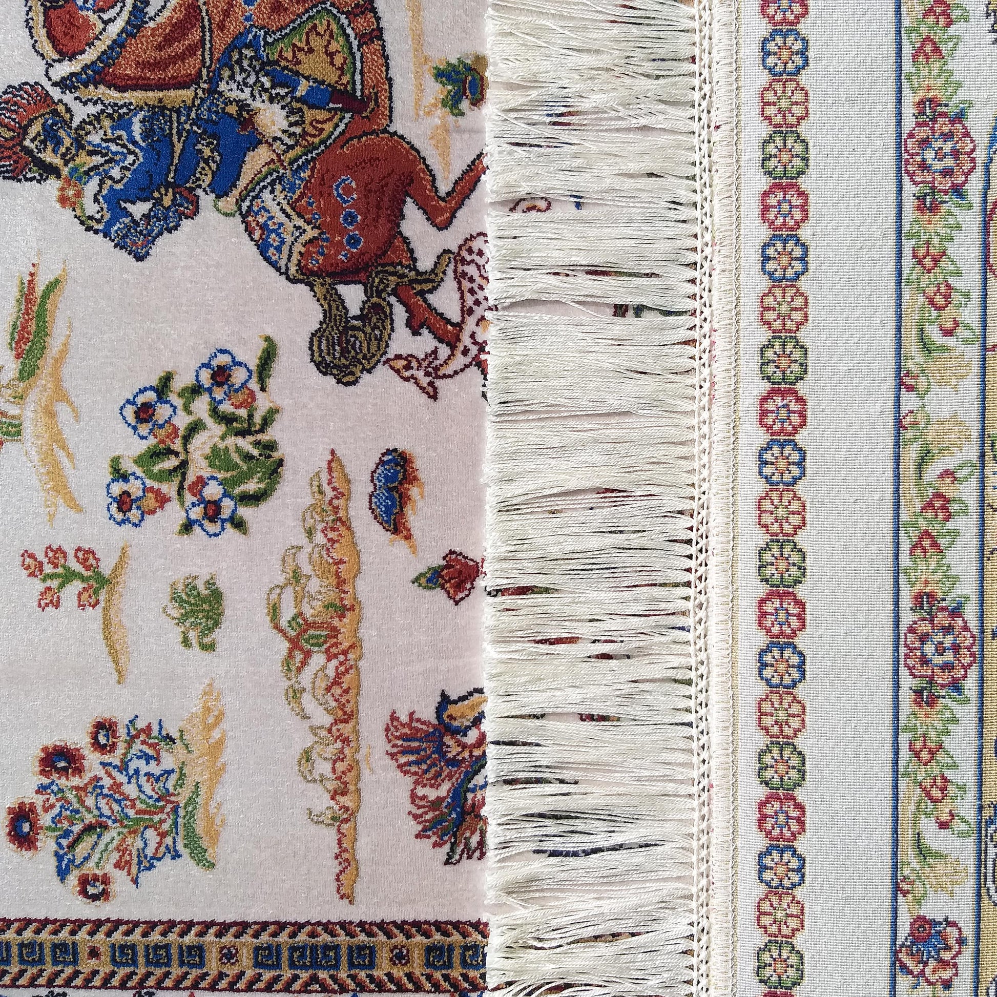 Tapis doux à motifs figuratifs et floraux complexes aux couleurs vives sur fond clair, franges et bordure tissée à fleurs