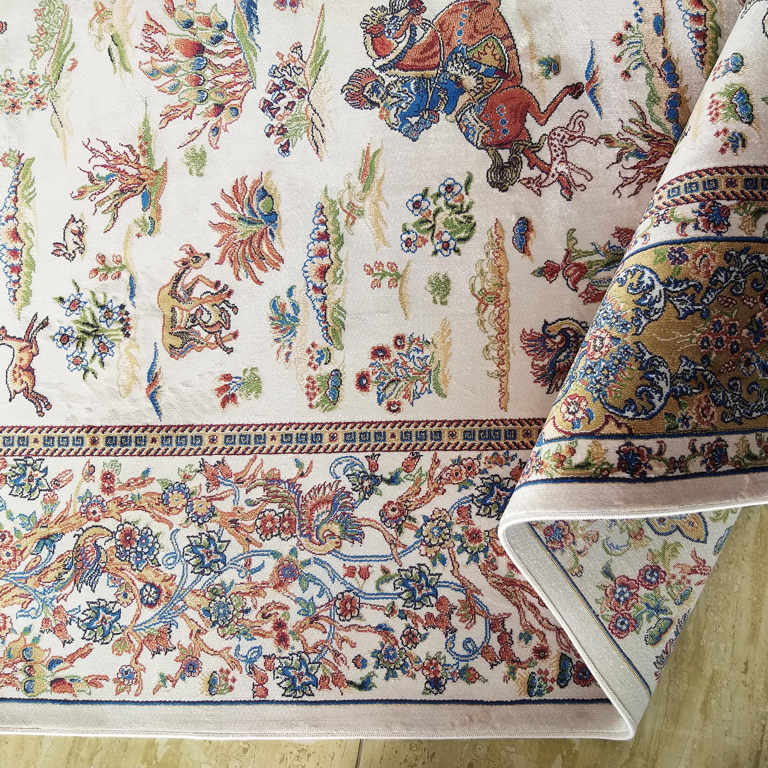 Tapis crème à motifs floraux et d'animaux stylisés, avec bordure détaillée et multicolore, partiellement roulé