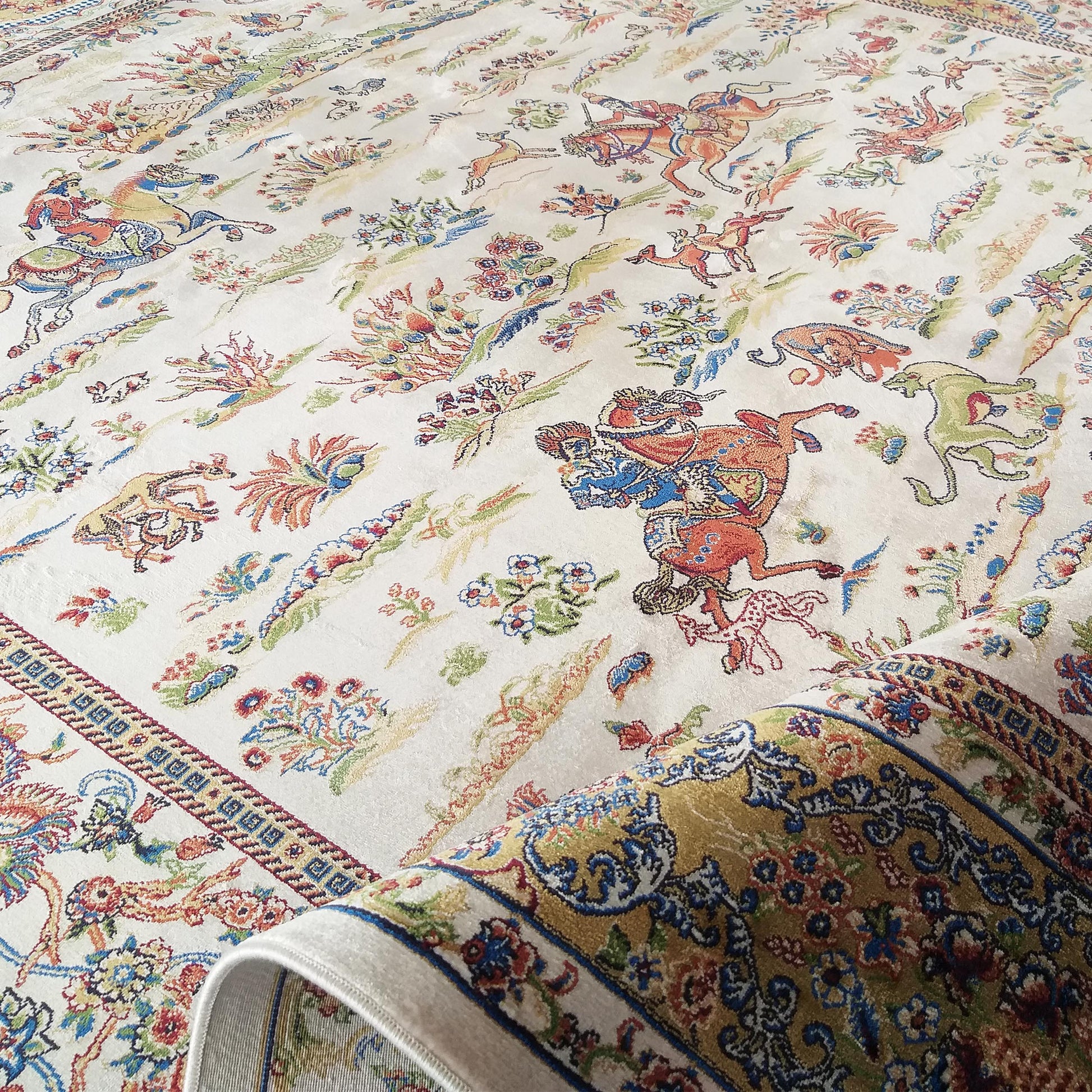 Tapis crème orné de motifs traditionnels colorés de chasseurs, animaux et fleurs. Sa bordure est dorée à motifs bleus et rouges