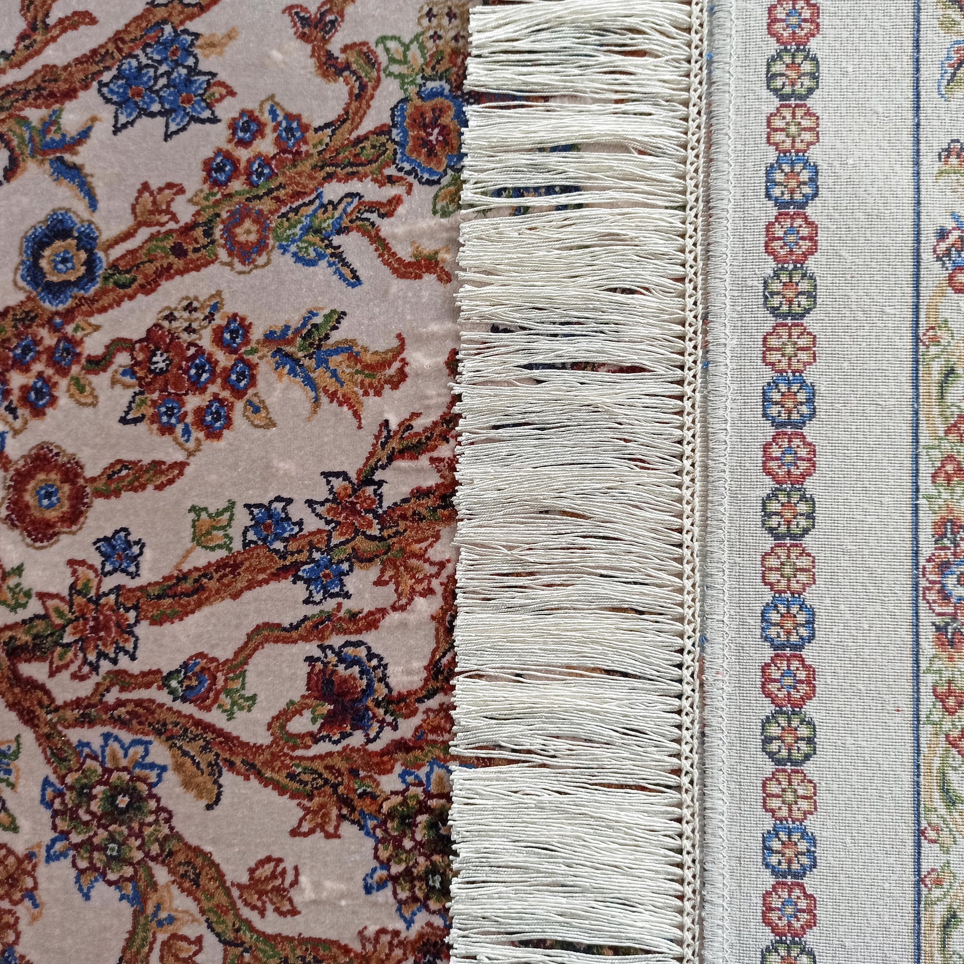 Tapis crème à motifs floraux colorés, avec une bordure tissée à franges et motifs géométriques