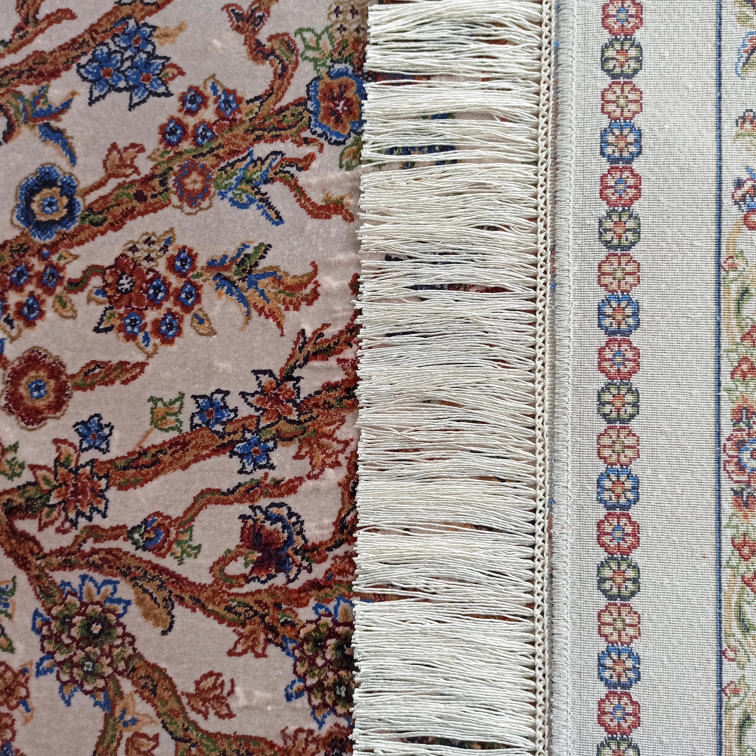 Tapis crème à motifs floraux colorés, avec une bordure tissée à franges et motifs géométriques