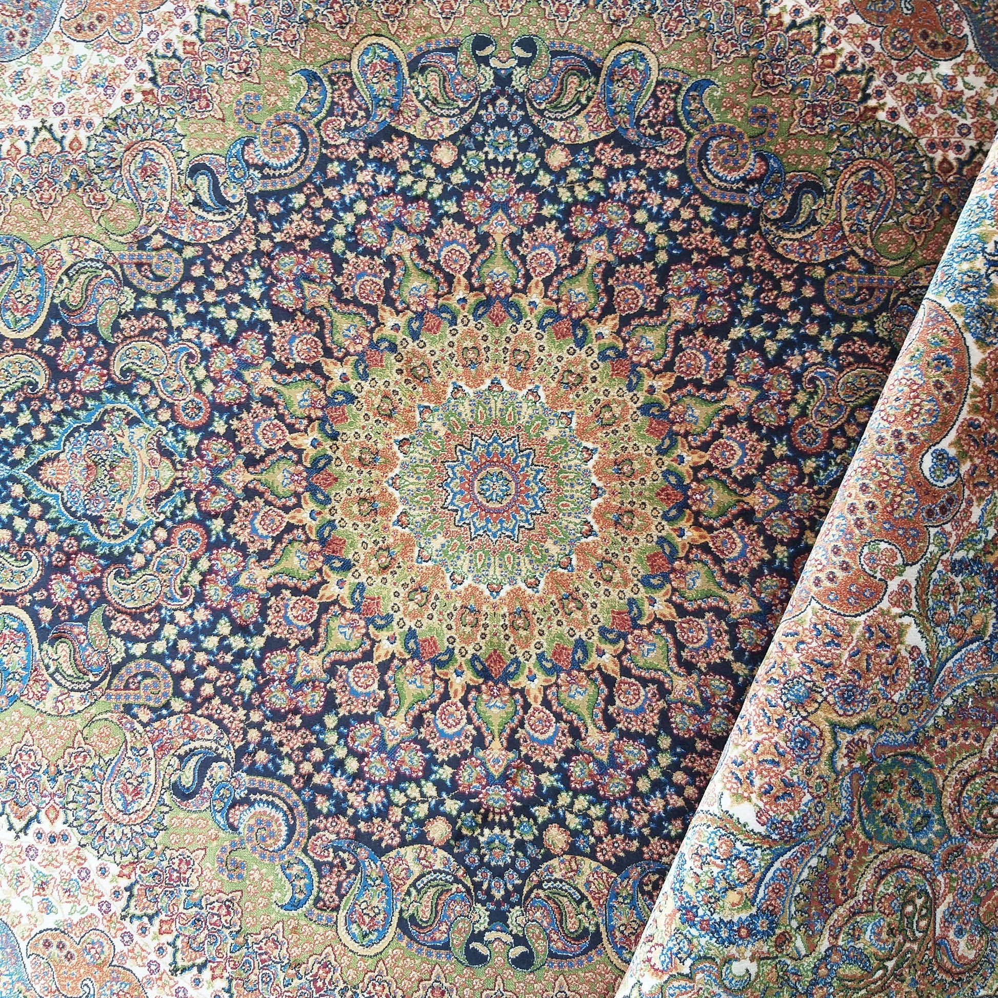 Tapis à motifs floraux et cachemire complexes autour d'un médaillon, en bleu marine, vert, or et rouge, avec une partie roulée