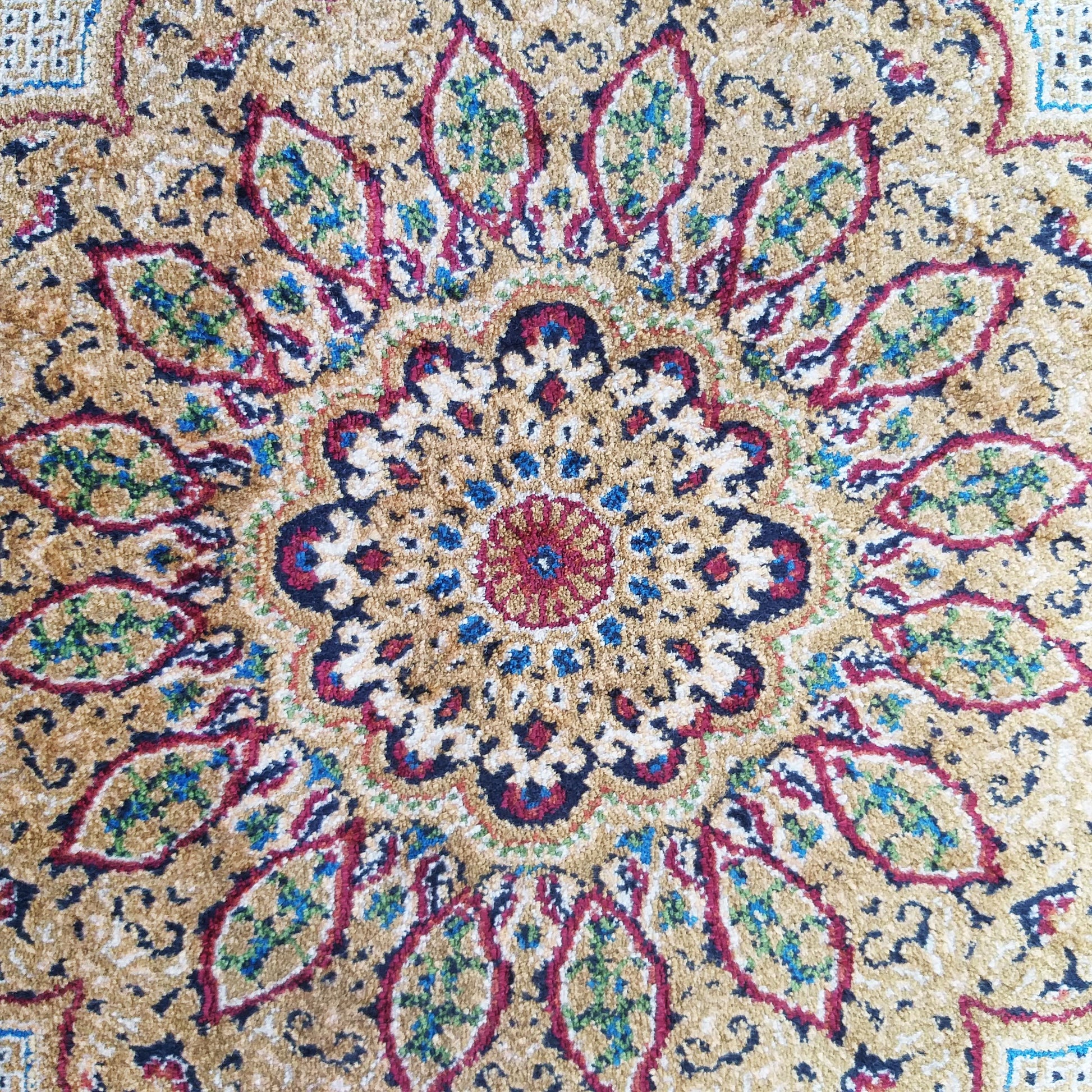Tapis beige doré à motifs floraux et géométriques complexes en médaillon central, avec du rouge, bleu, vert, blanc et noir