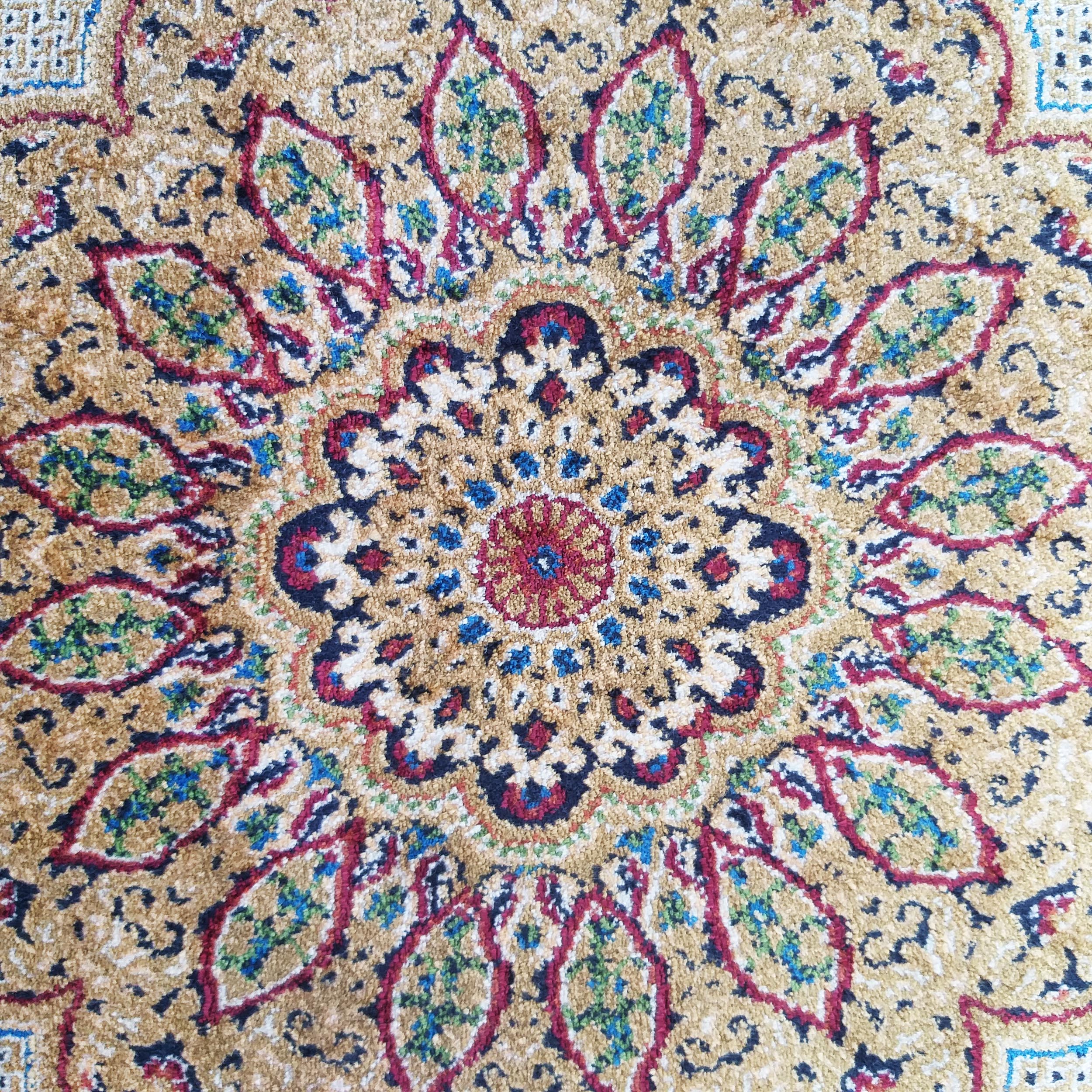 Tapis beige doré à motifs floraux et géométriques complexes en médaillon central, avec du rouge, bleu, vert, blanc et noir