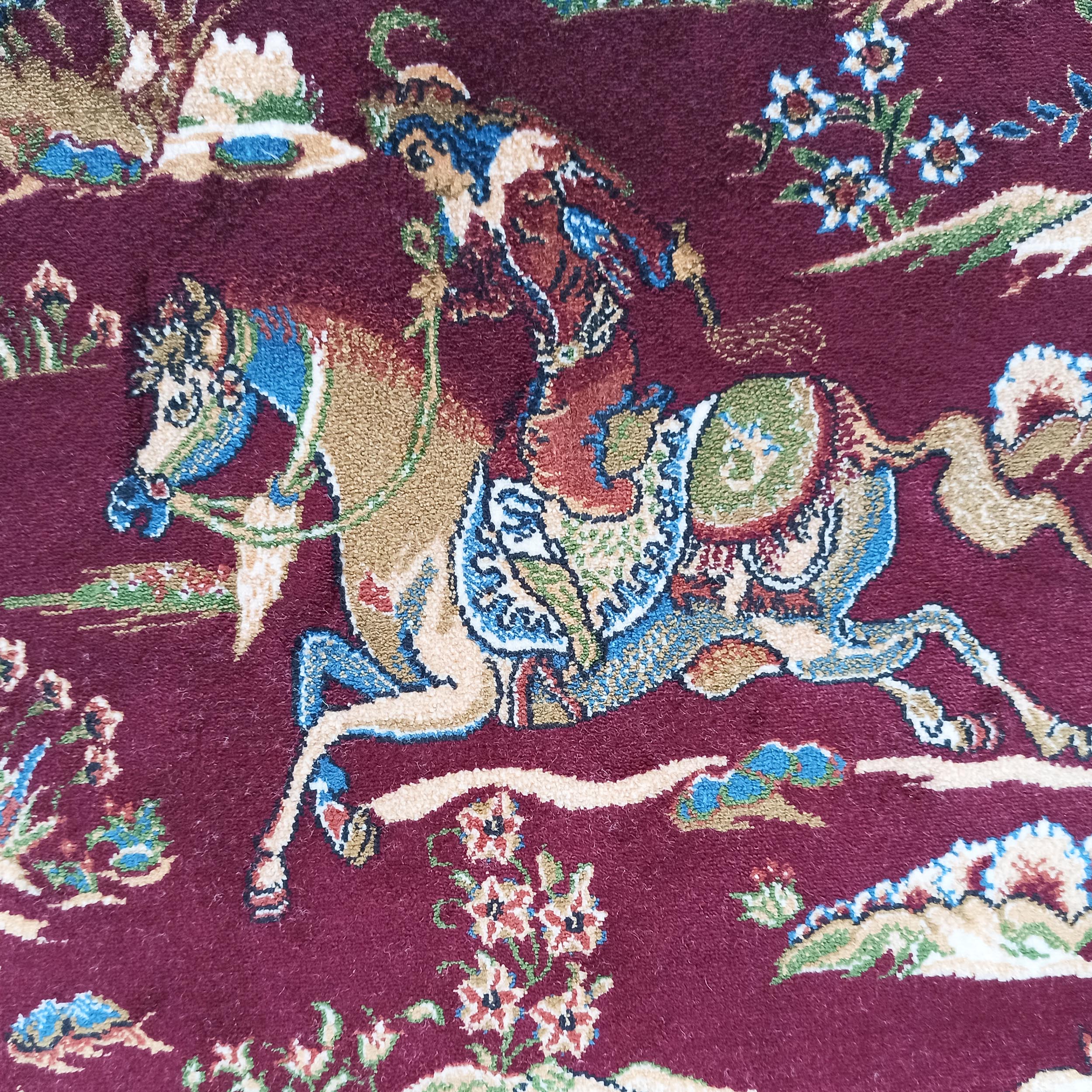 Tapis bordeaux à motifs traditionnels représentant un cavalier sur son cheval avec des fleurs et des paysages