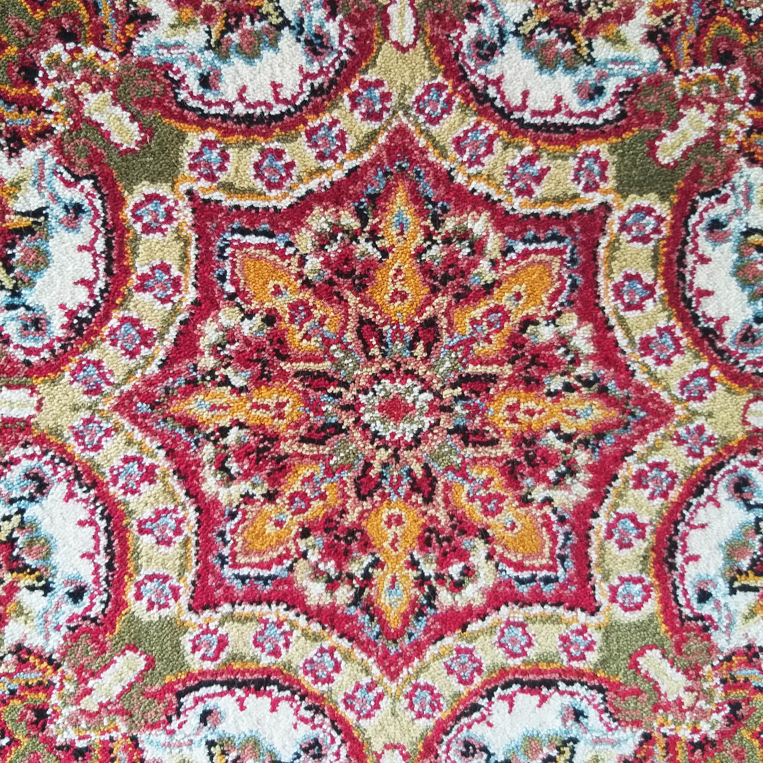 Tapis textile aux motifs floraux et géométriques intriqués, richement coloré en rouge, orange, blanc, bleu et vert olive