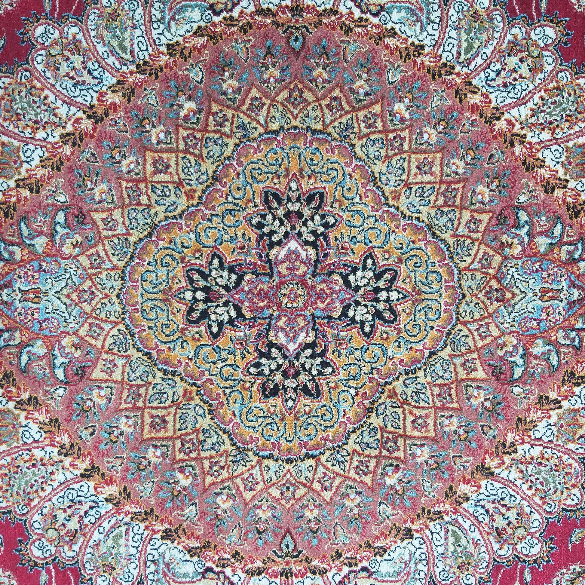 Tapis à motifs floraux et géométriques complexes. Dominante rouge et or avec détails bleus, noirs et crème au centre