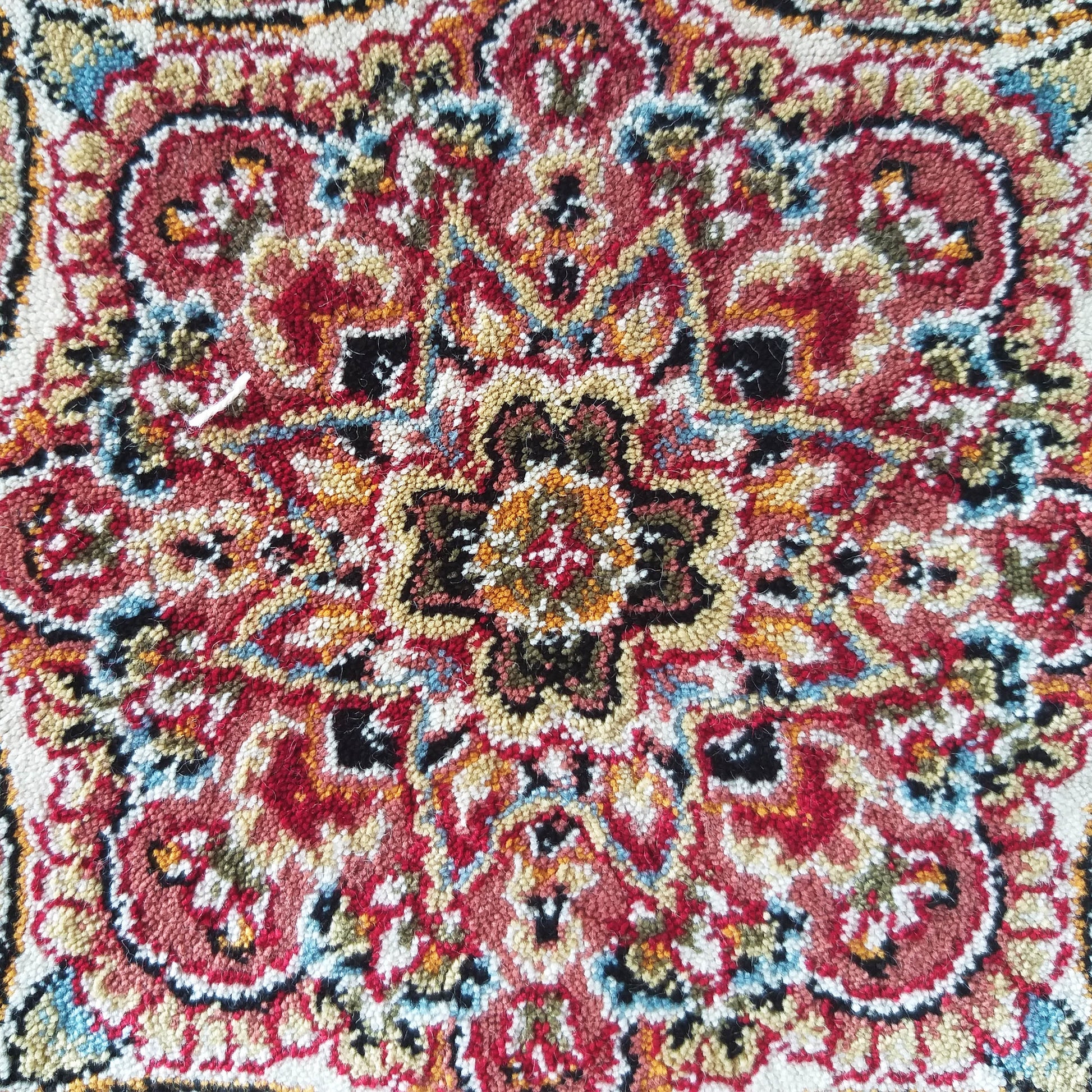 Tapis aux motifs complexes et floraux en rouge, or, noir, crème et bleu, avec une texture dense de fils colorés