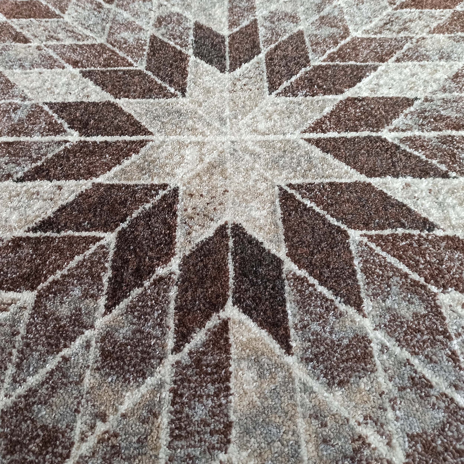 Tapis à poils longs et texture moelleuse, motif étoilé géométrique aux teintes de marron, beige et blanc cassé
