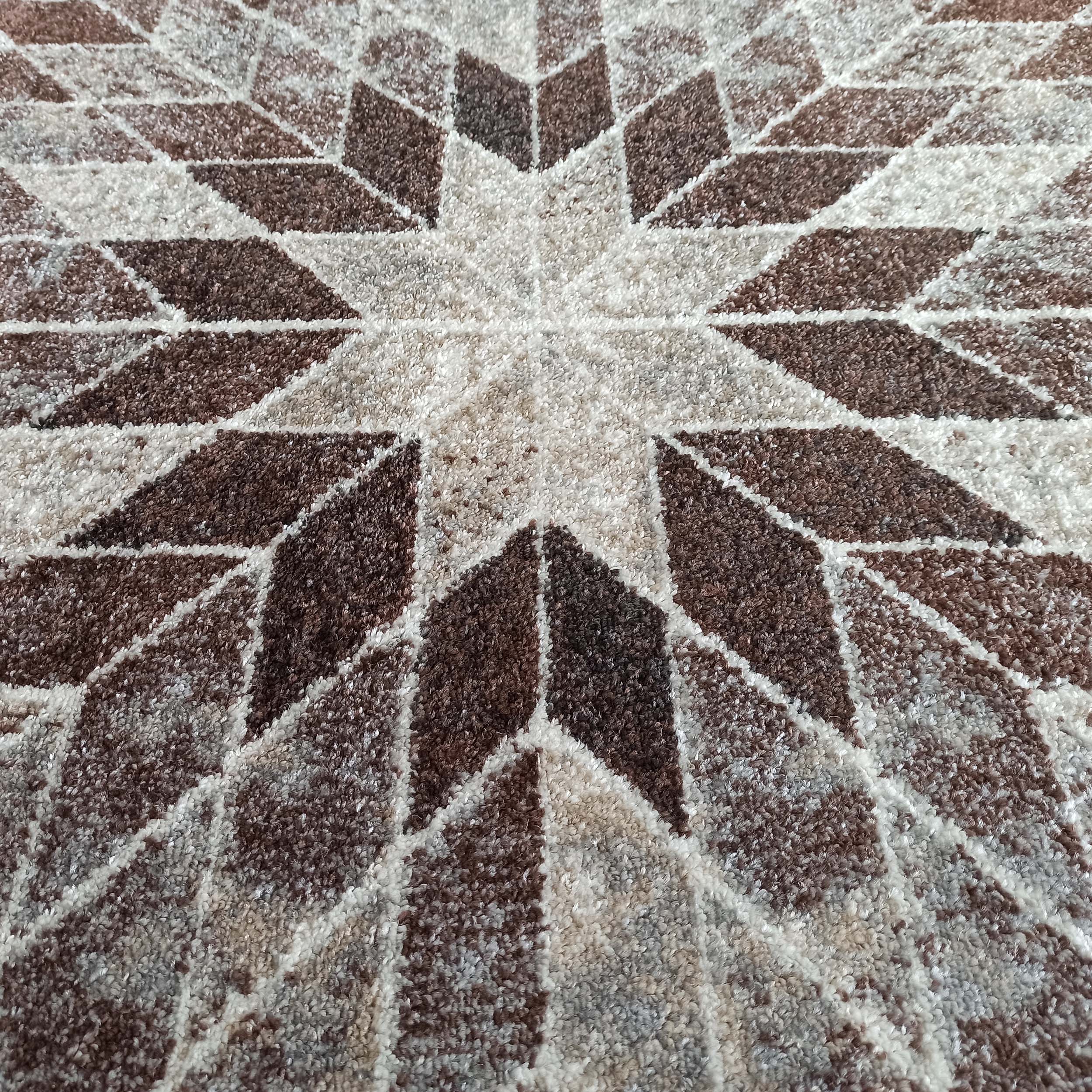 Tapis à poils longs et texture moelleuse, motif étoilé géométrique aux teintes de marron, beige et blanc cassé