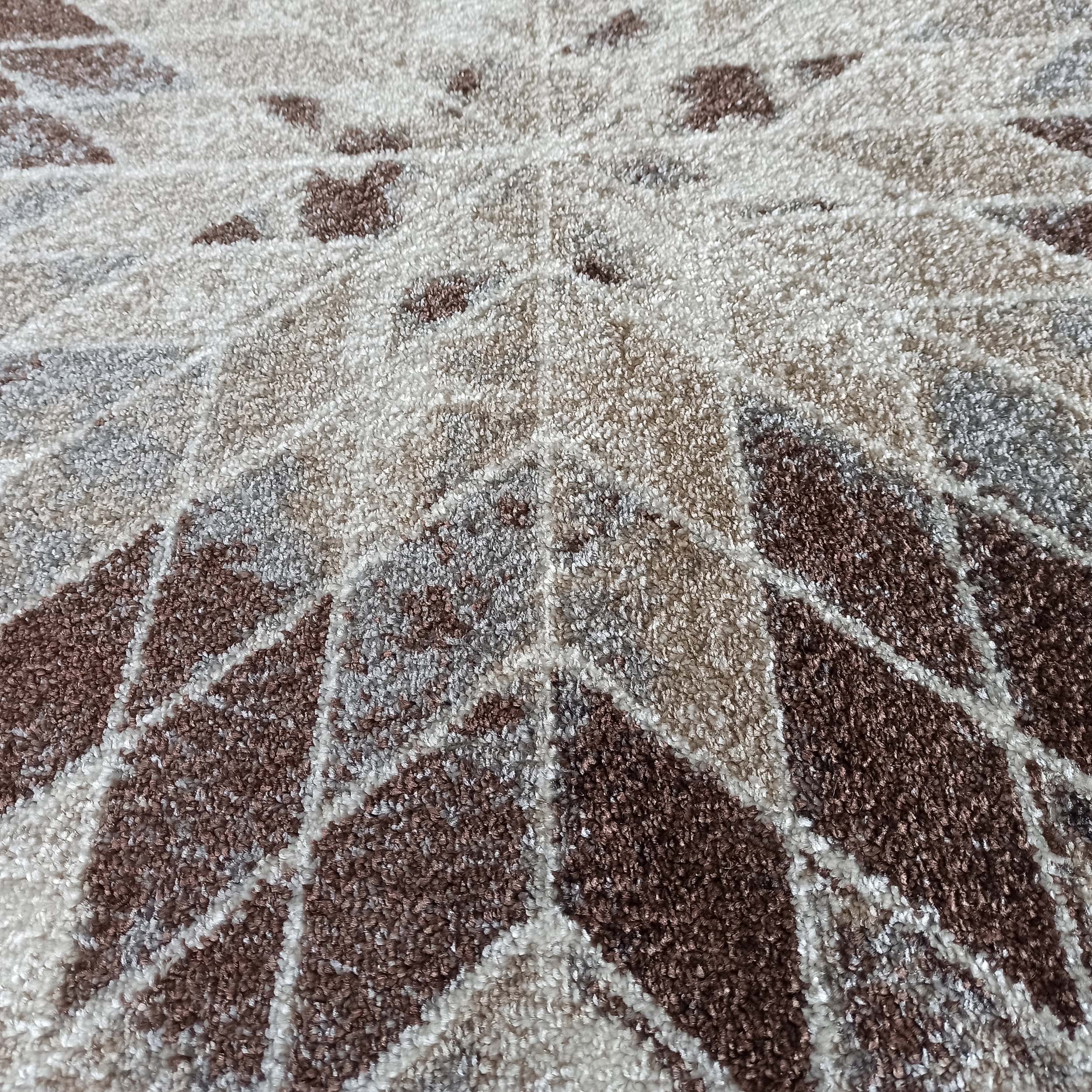 Tapis à poils épais affichant un motif géométrique radial de losanges et triangles en marron, beige et blanc crème