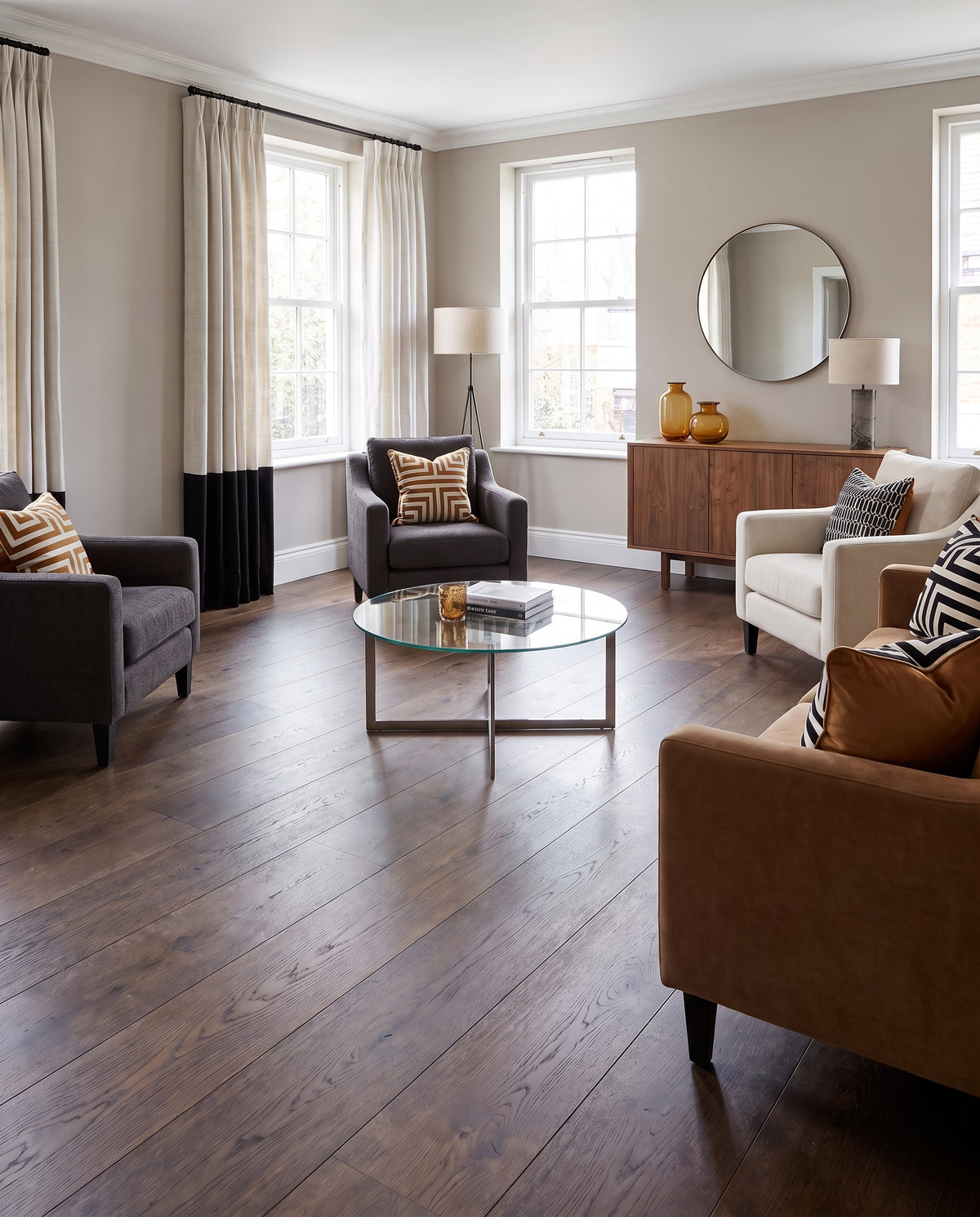 Parquet foncé pour ce salon meublé de fauteuils et d'une table basse ronde en verre, pièce sans tapis
